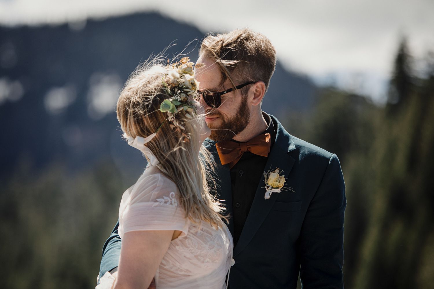 Couple sharing intimate moment with mountain landscape in background.