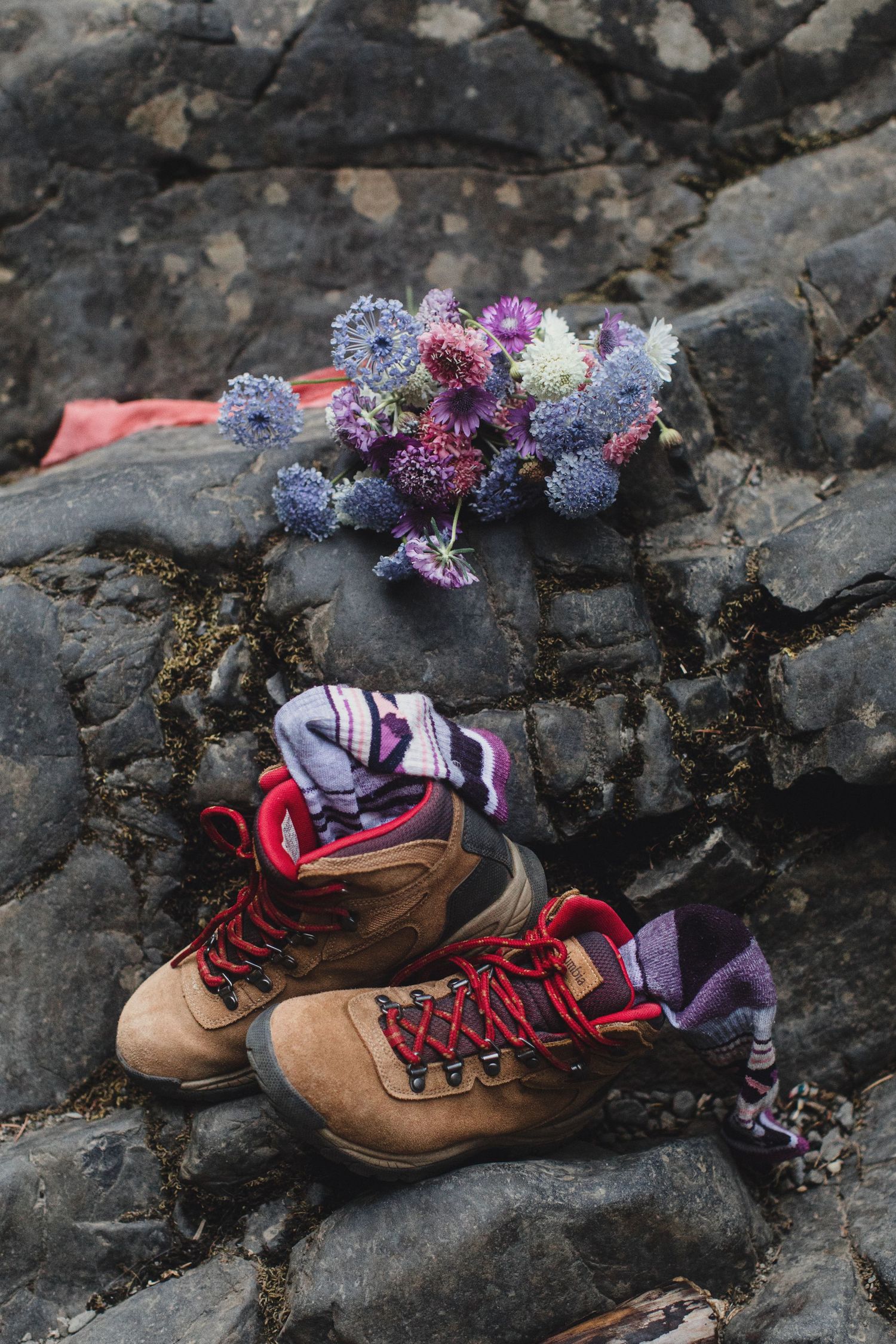 Hiking boots and wildflower bouquet resting on rocky terrain for an adventure elopement.