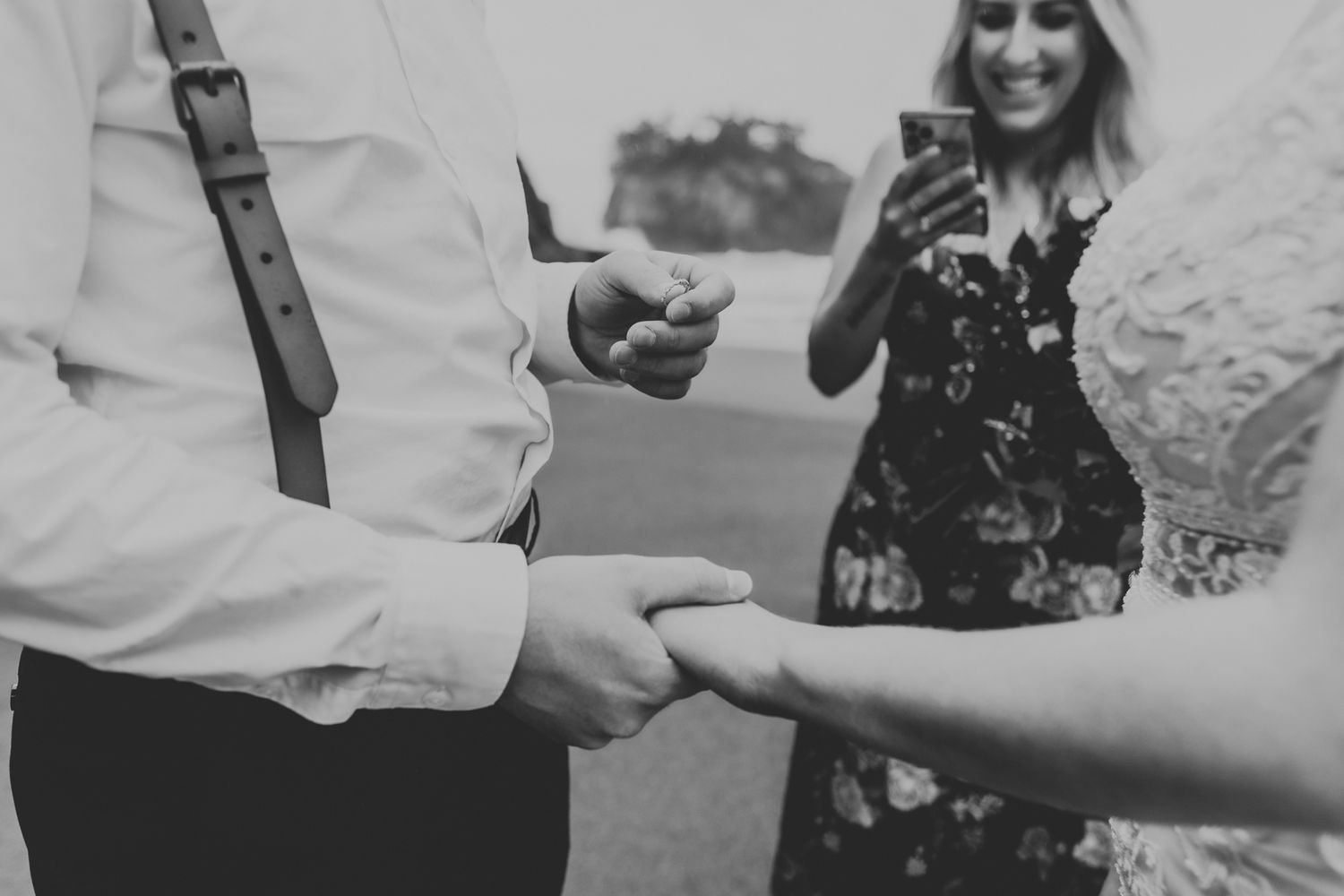 A black and white close-up shot of hands exchanging rings during a wedding ceremony.