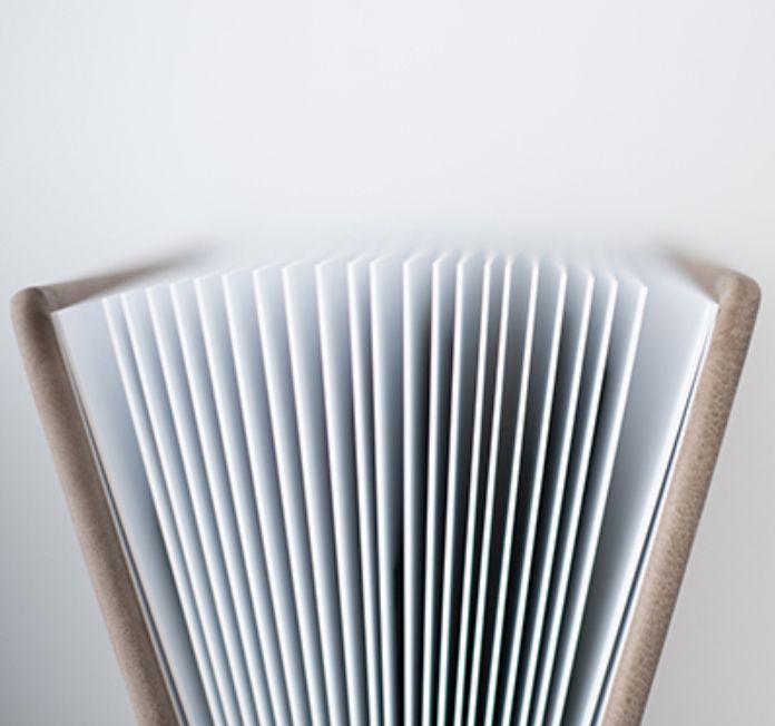 Close-up of an open book with fanned pages creating a symmetrical accordion pattern against a white background.