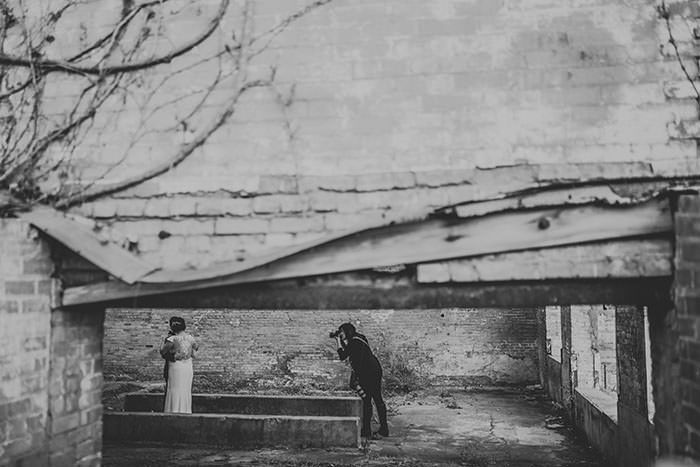 Black and white photo of a couple posing in a rustic brick archway during an engagement shoot.