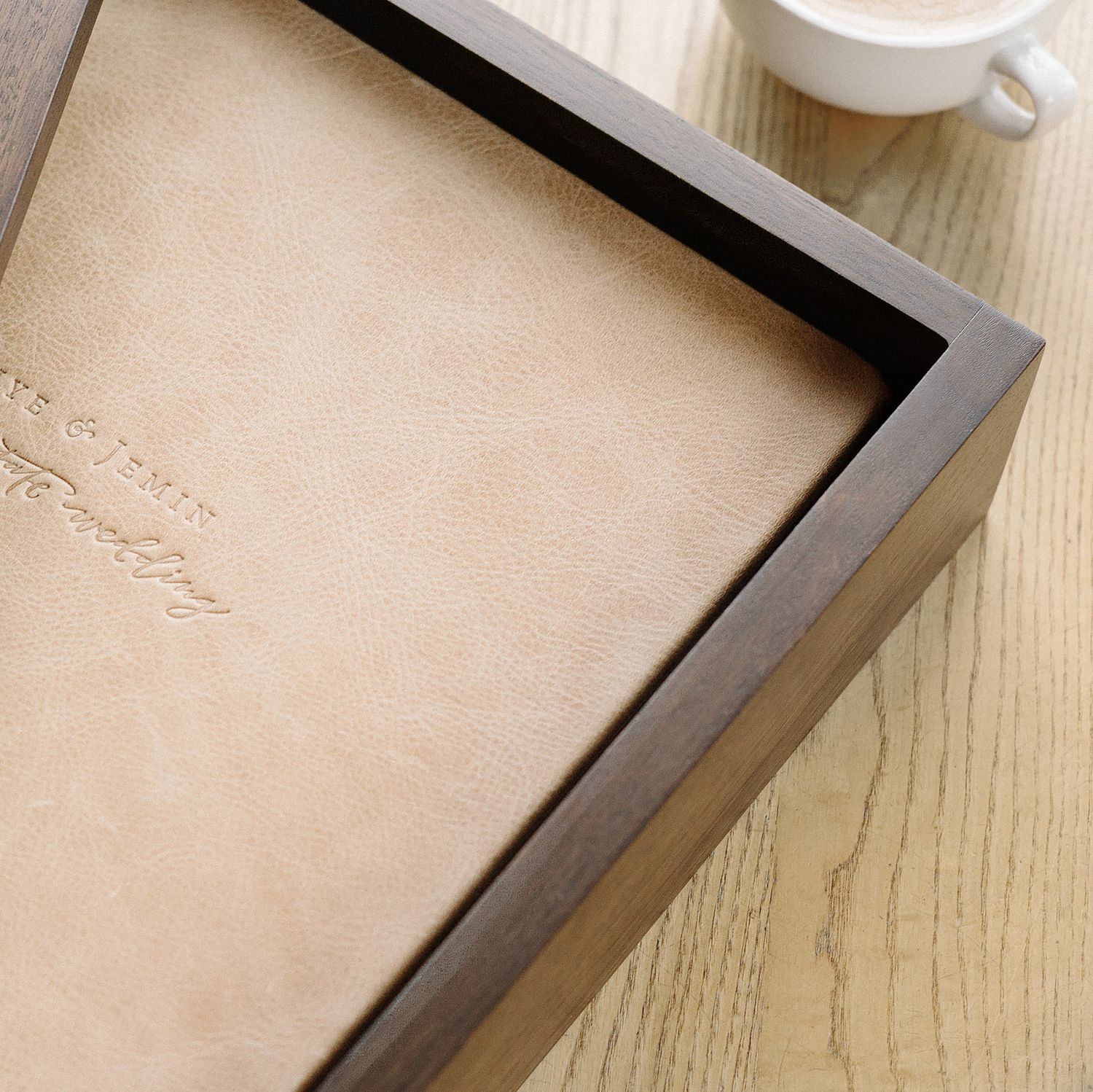 Close-up of a personalized leather journal in a dark wooden box frame, with embossed text, placed on a wooden surface.