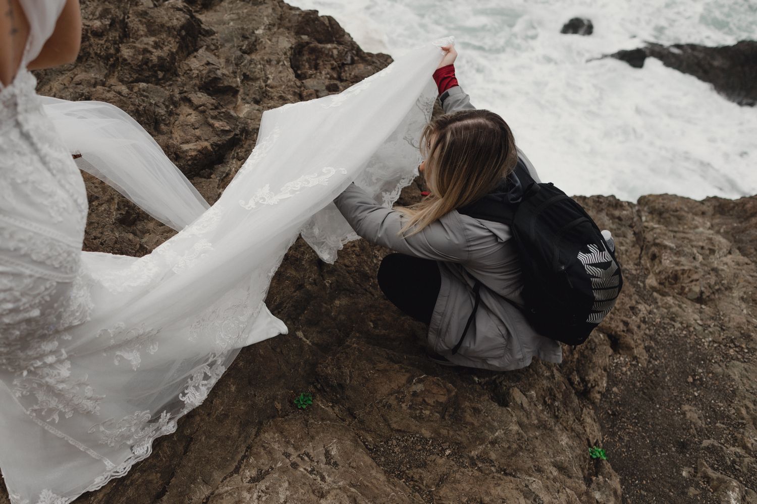 Wedding dress billowing in the wind on rocky coastal overlook.
