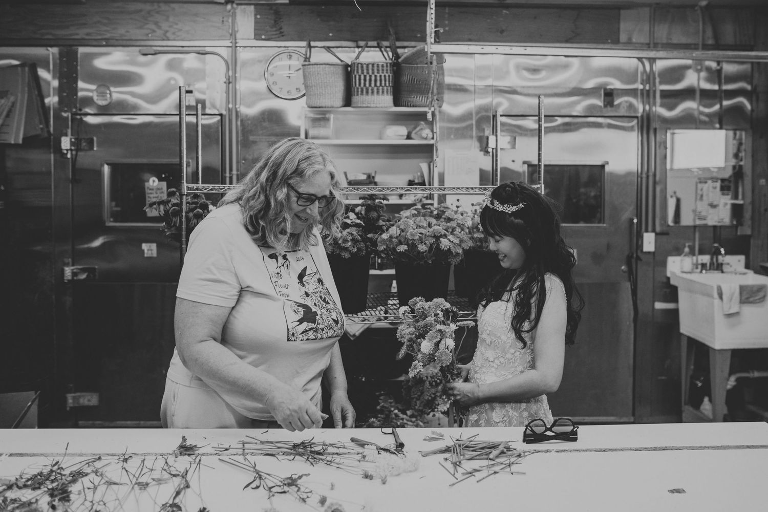 Black and white photo of two women arranging flowers in a professional kitchen.