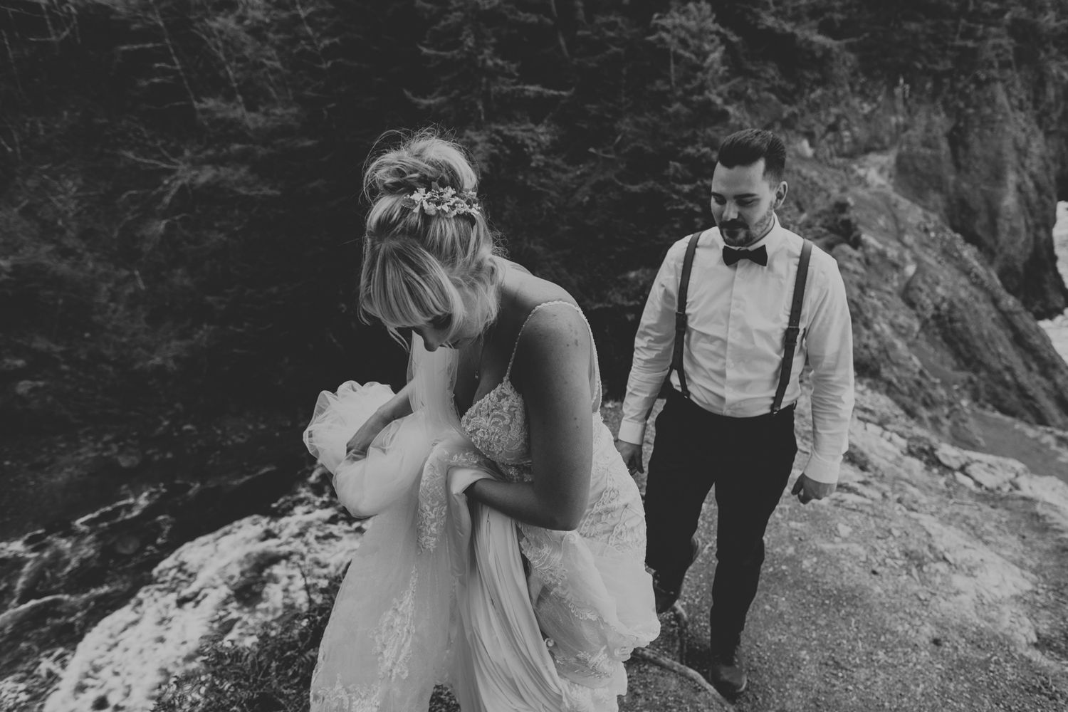 An intimate black and white wedding moment captured against rugged coastal cliffs.