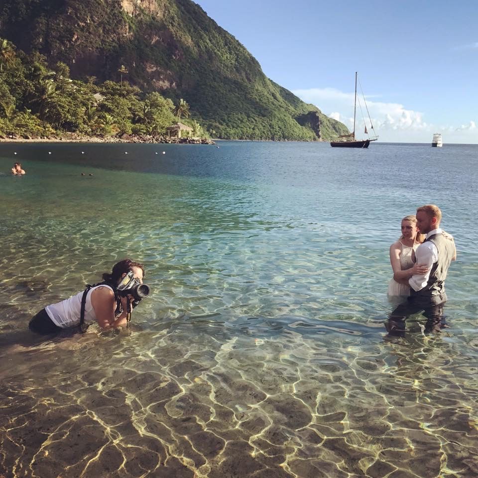 Elopement photographer poses a couple in the water in Saint Lucia preparing for an underwater shot in front of the Pitons