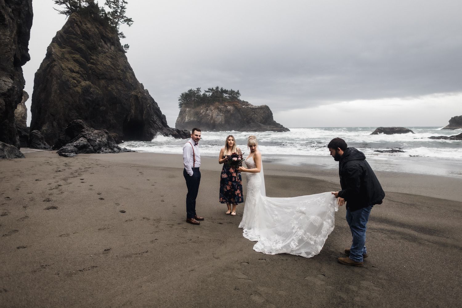 A wedding ceremony taking place on a stormy beach with dramatic rock formations and ocean waves.