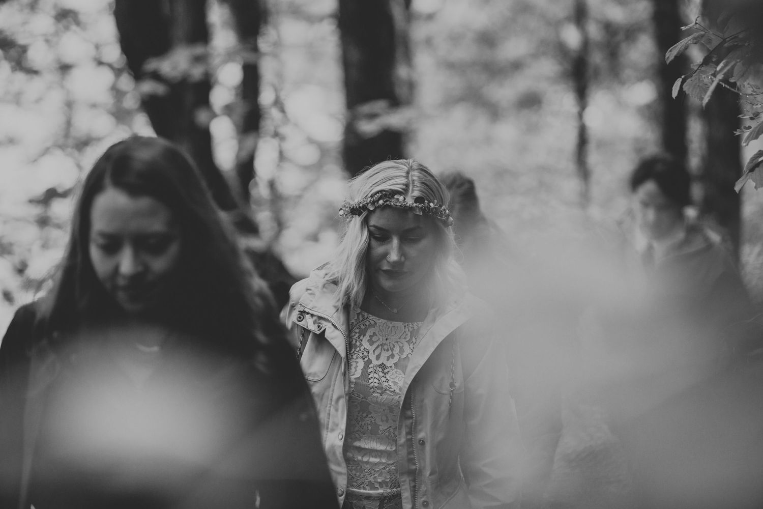 A black and white artistic wedding photo capturing guests in a misty forest setting.