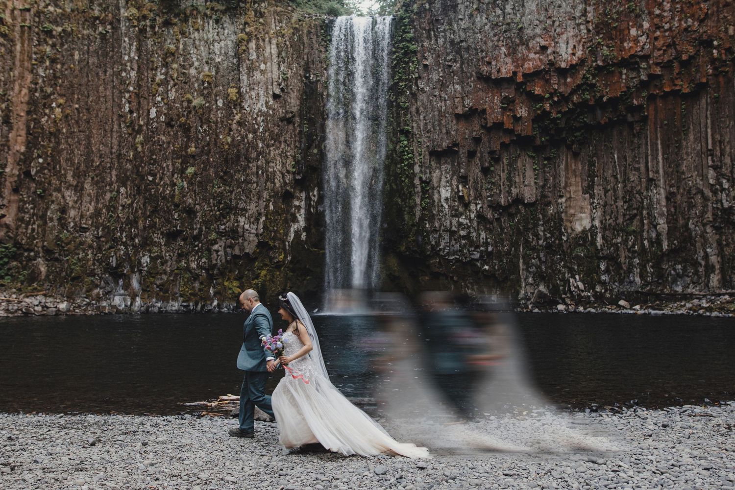 Bride and groom embracing in front of a stunning waterfall on their wedding day.