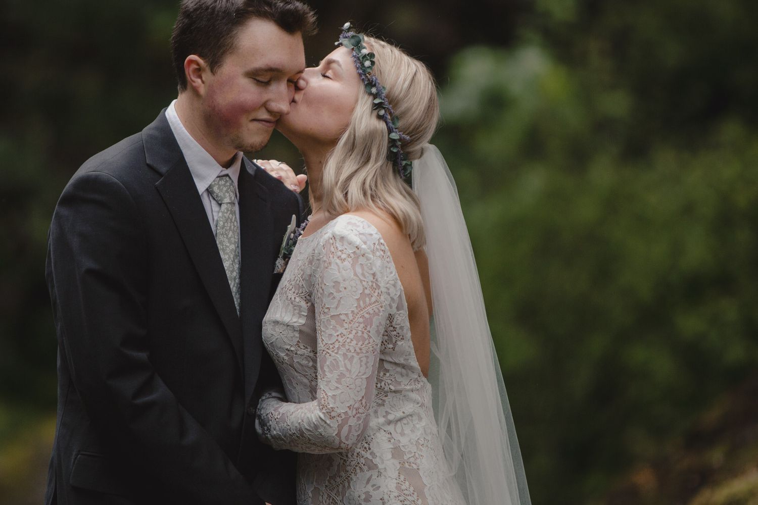 Intimate wedding moment captured between couple with bride wearing lace dress and flowing veil.