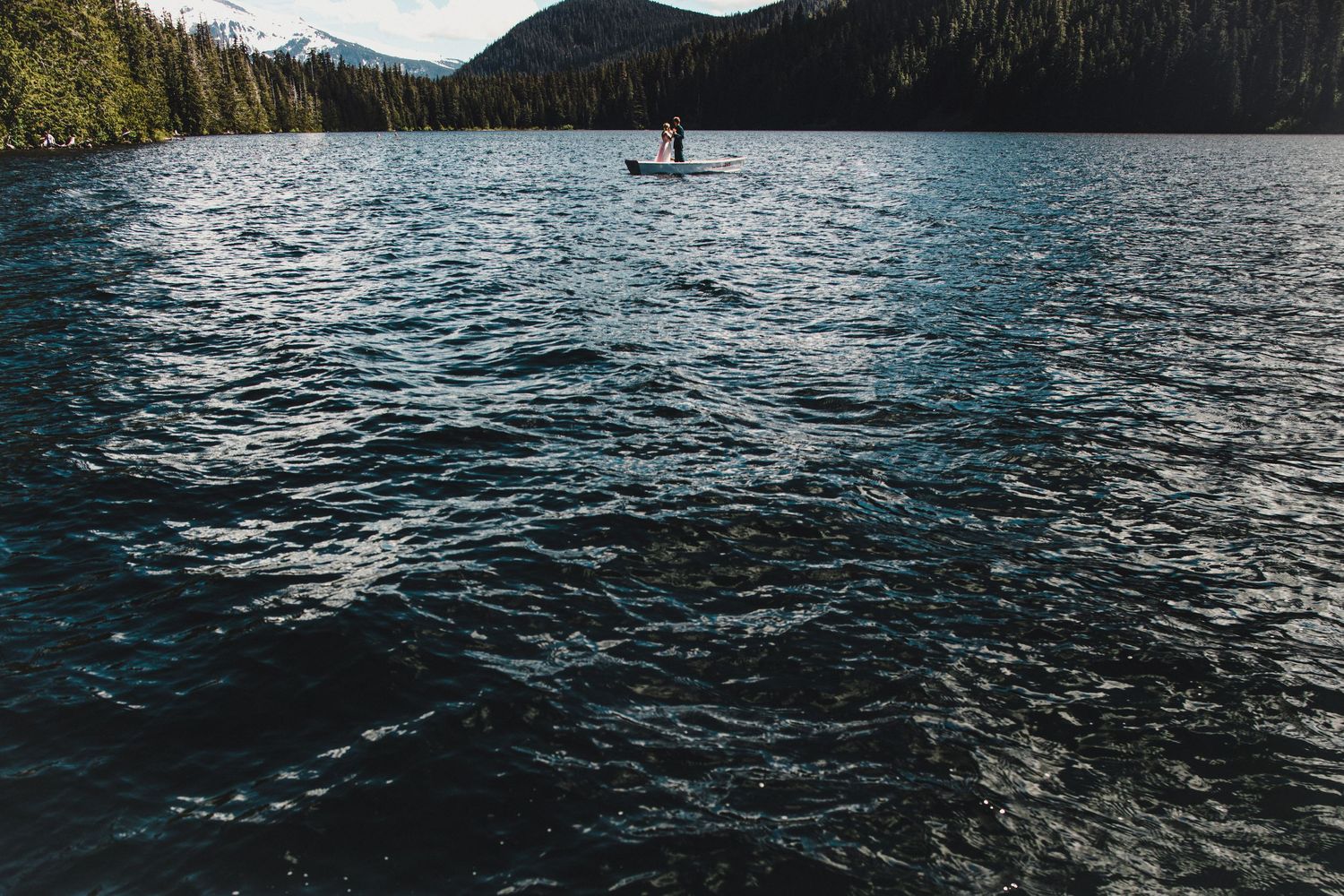 Rippling blue waters of mountain lake with distant boat silhouette.