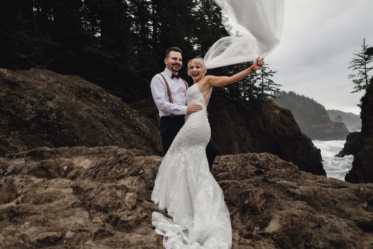 A joyful moment with billowing veil captured on dramatic coastal cliffs.
