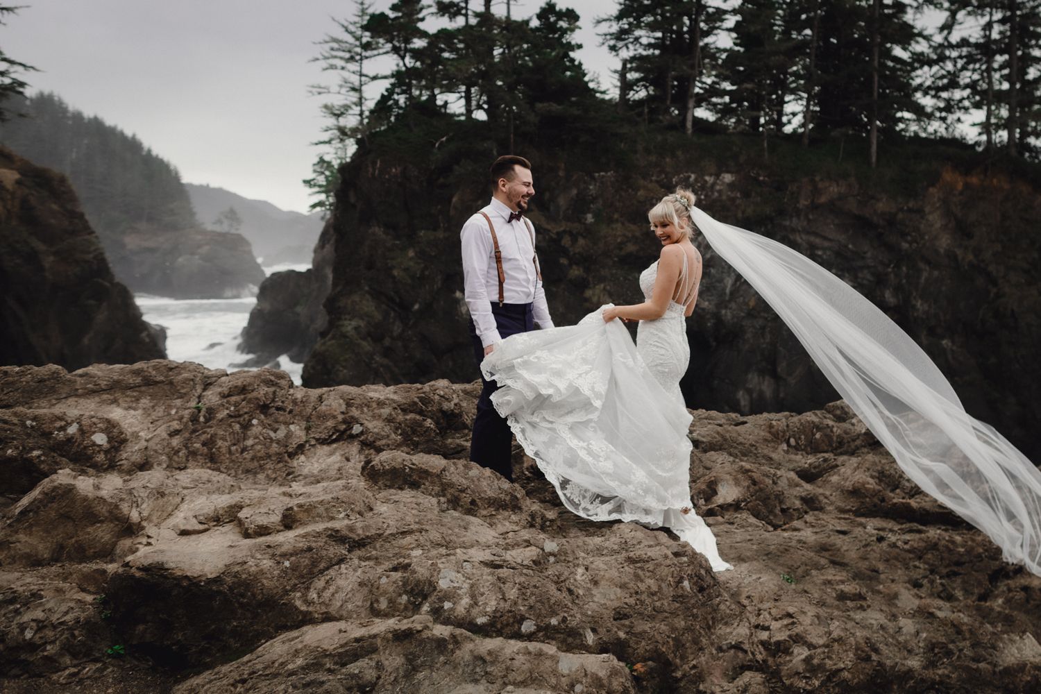 A flowing wedding dress and veil catch the wind on a dramatic Pacific Northwest coastline.