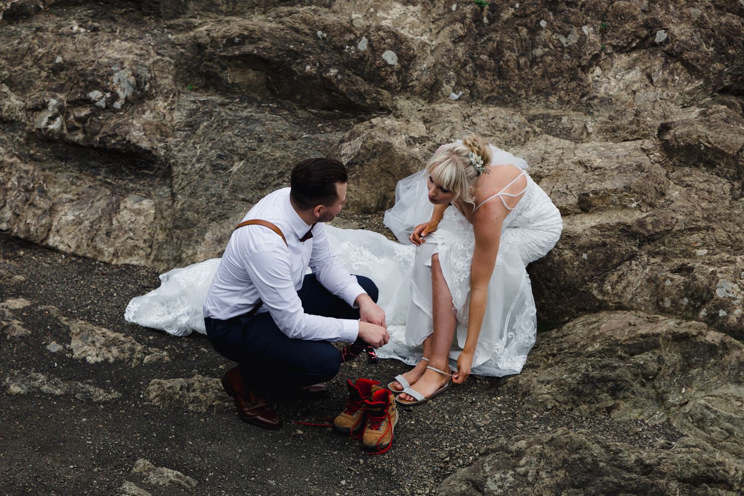 A sweet moment captured on rocky coastal terrain during an intimate outdoor wedding.