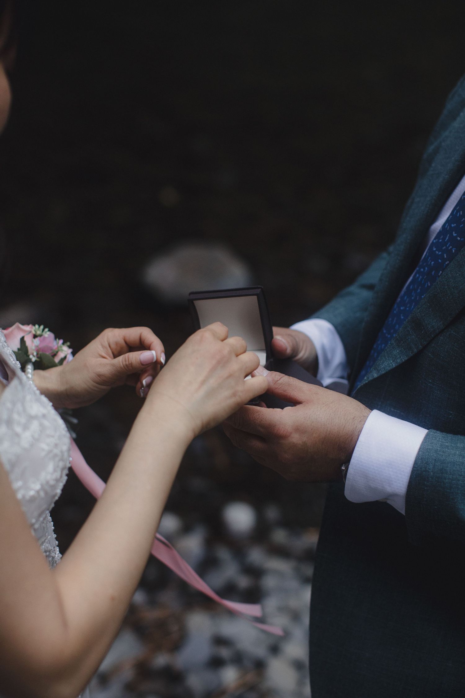 Bride and groom exchanging wedding rings during an outdoor elopement ceremony.