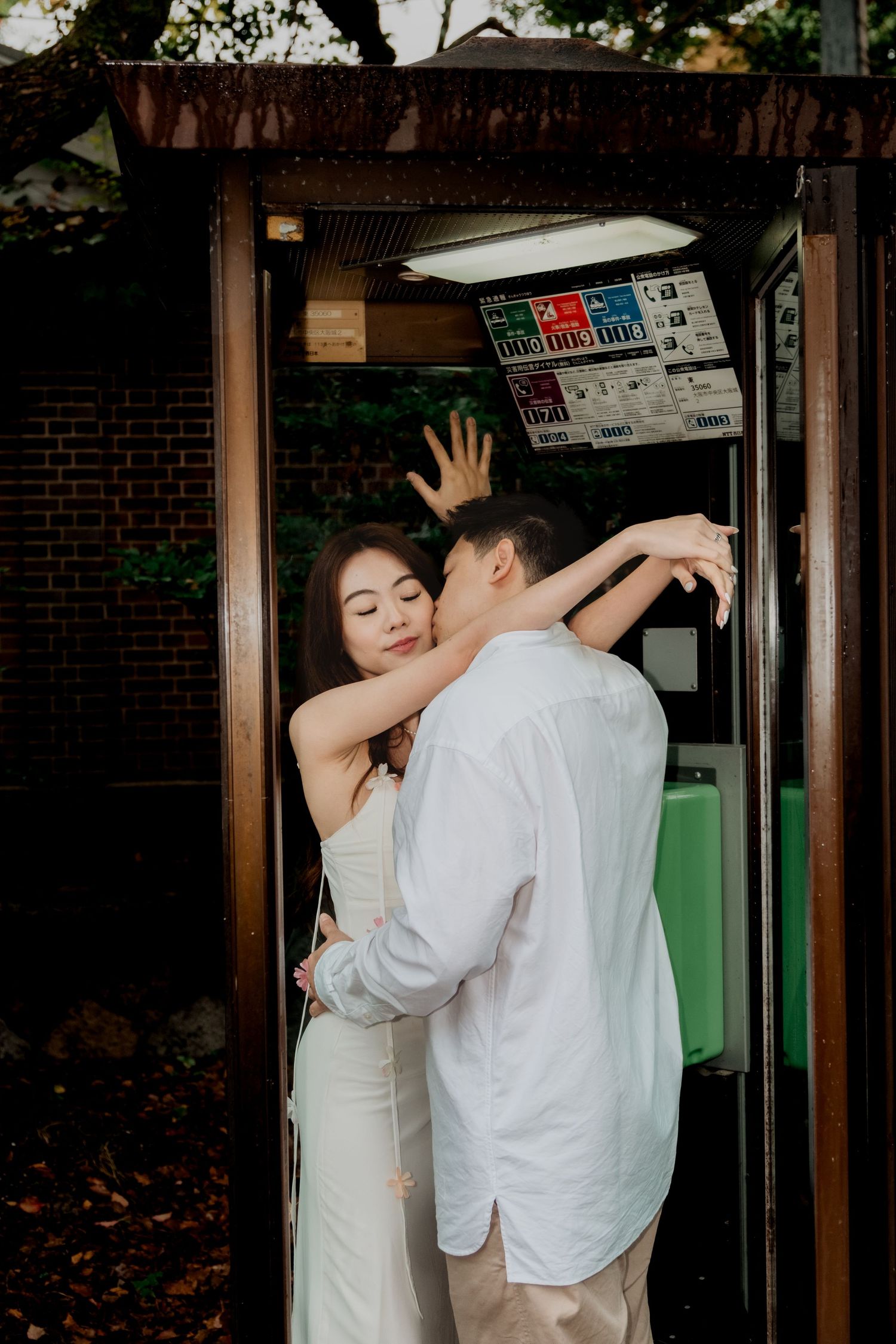 Destination pre-wedding photoshoot of Romantic moment between couple in formal wear at vintage phone booth in Japan.