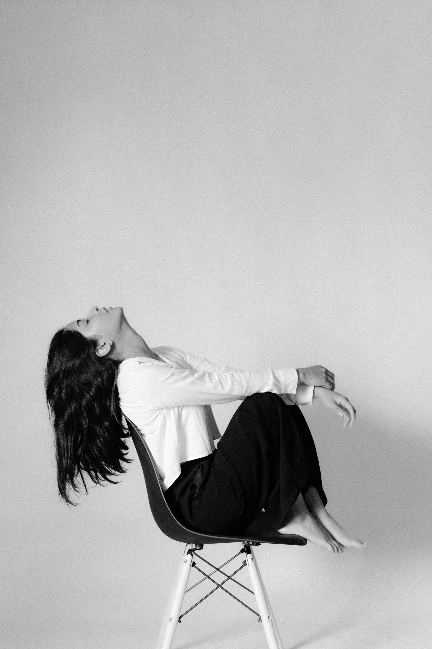 Artistic black and white photo of someone reclining dramatically on a modern chair.