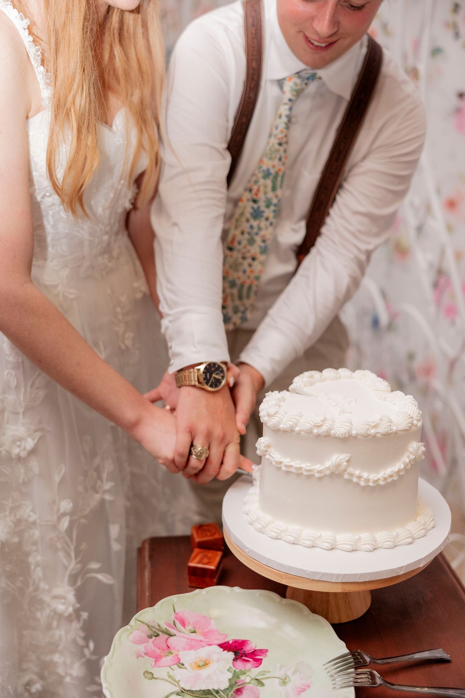 Couple cutting their simple white two-tier wedding cake together.