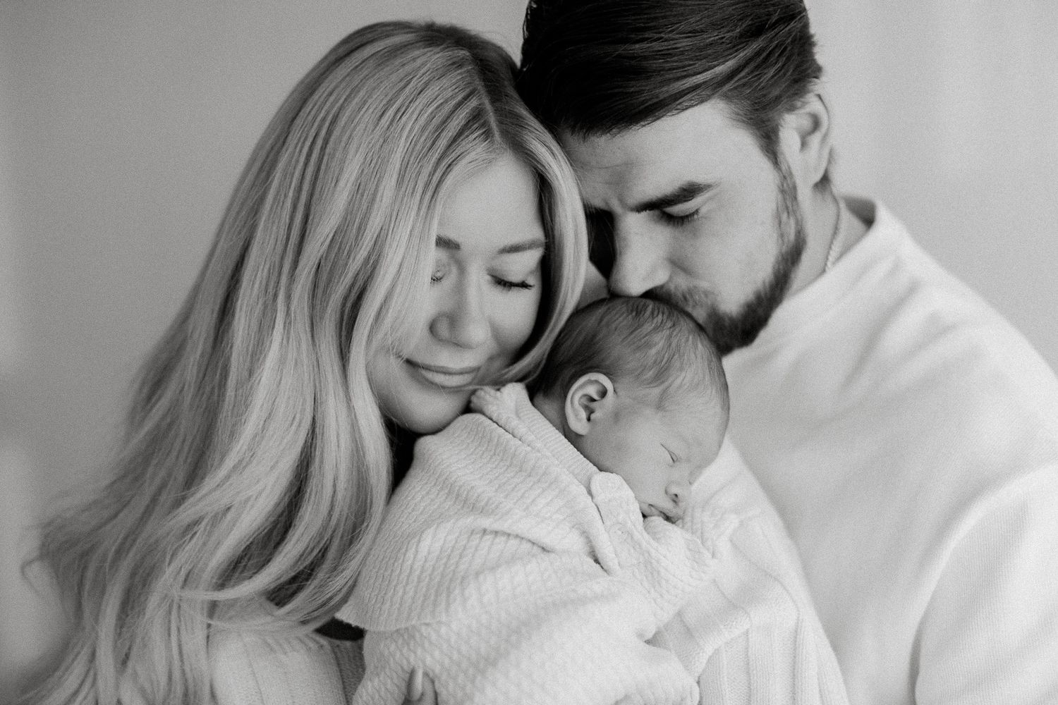 Newbornkuvaus studiolla Tampereella, vauva vanhempien sylissä tunnelmallisessa mustavalkoisessa lähikuvassa.