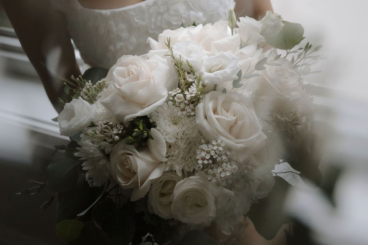 Delicate white roses and baby's breath arranged in an elegant wedding bouquet with soft natural lighting.