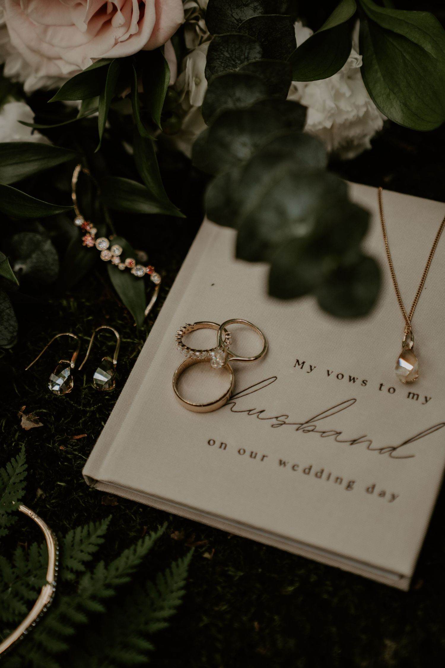 wedding rings on a vow book with pendant necklace