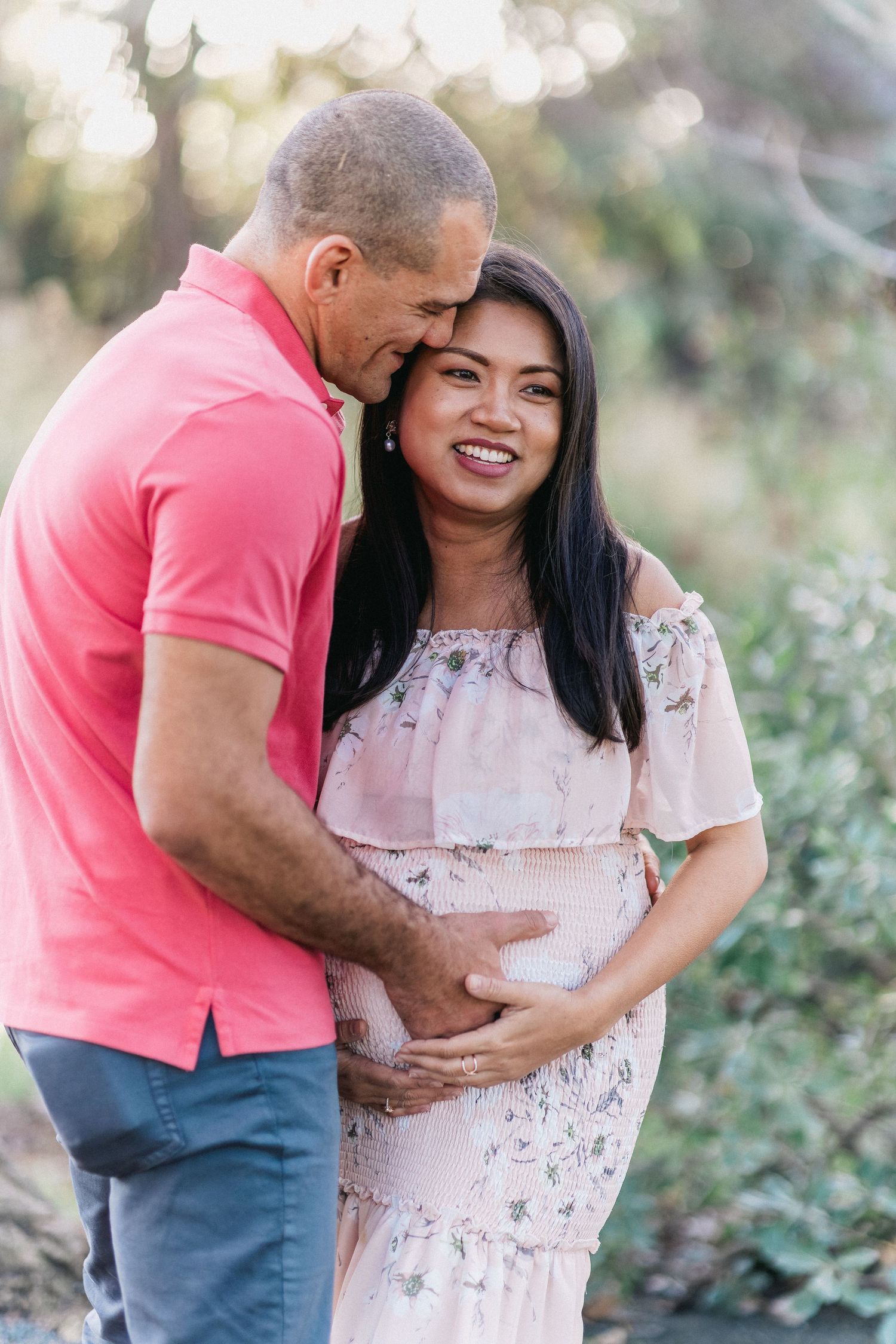 Tender moment between couple during outdoor maternity photoshoot.