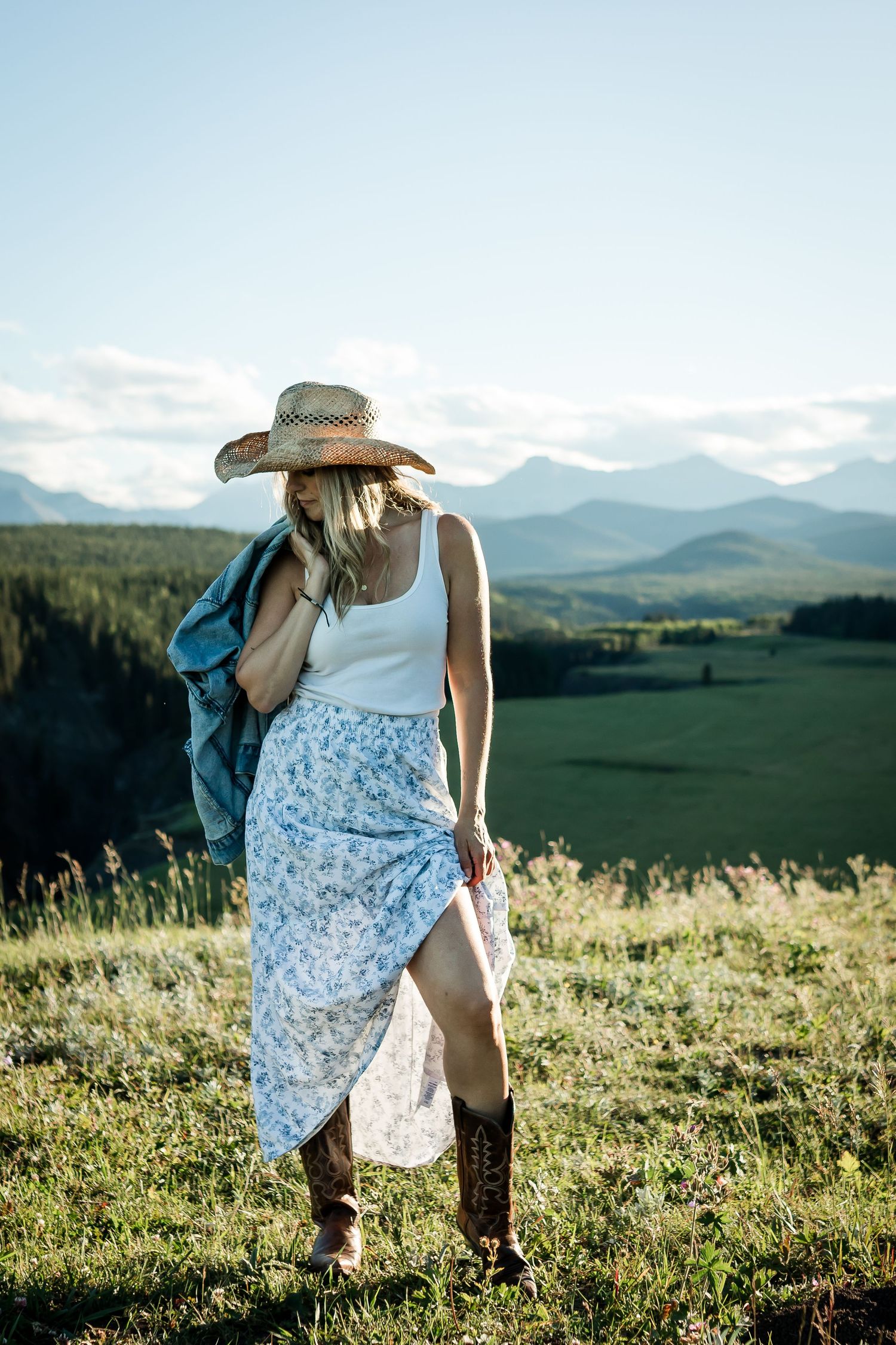 Portrait photography: Woman in Kananaskis mountains at golden hour against rolling hills and bright sky.