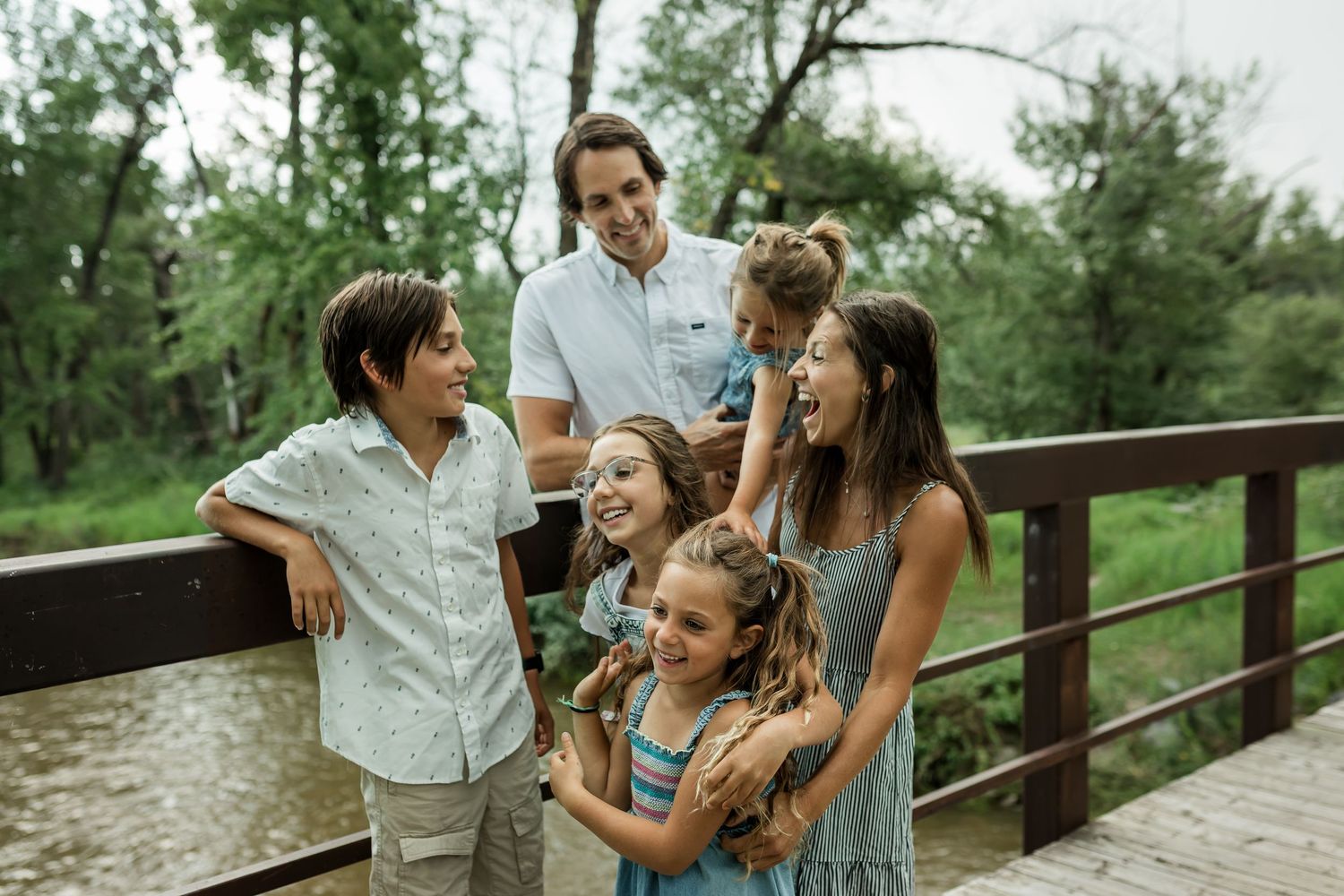 Family laughing together on bridge during summer family photography session in Calgary