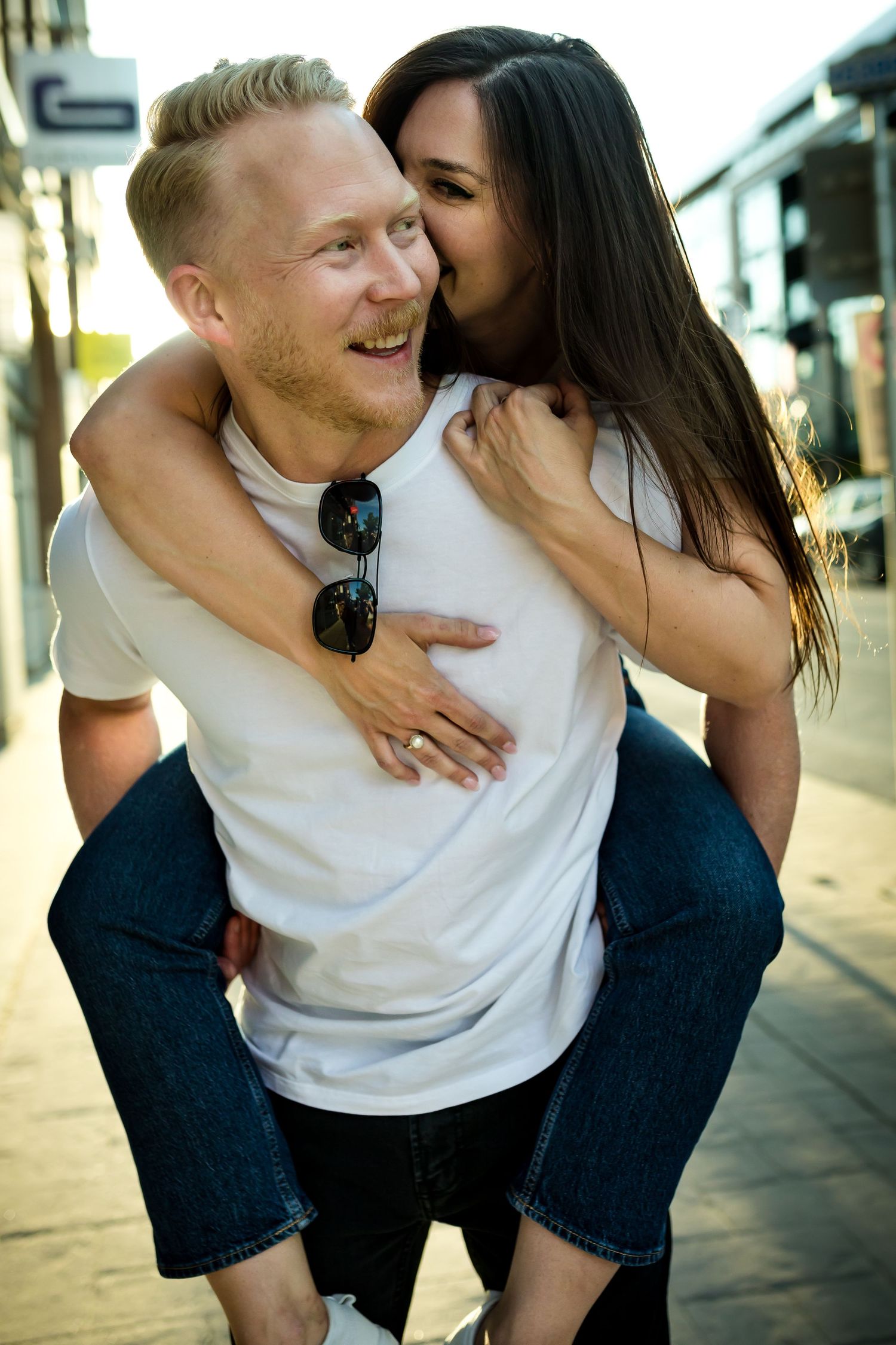 Calgary couple enjoying a piggy back ride during a  casual golden hour engagement photography session in Calgary