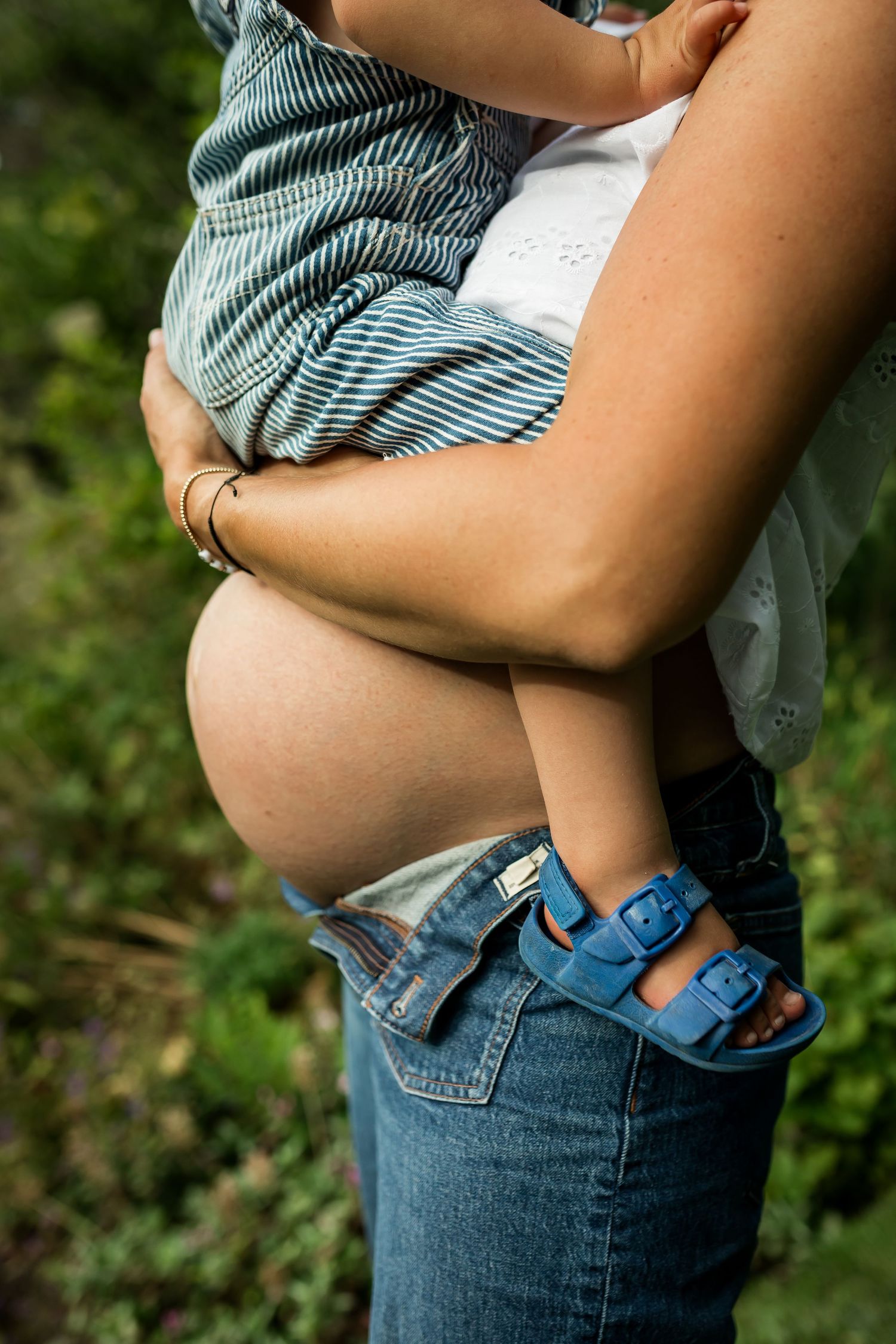 Expecting mother cuddling toddler son with baby bump during lifestyle maternity photography session in Calgary