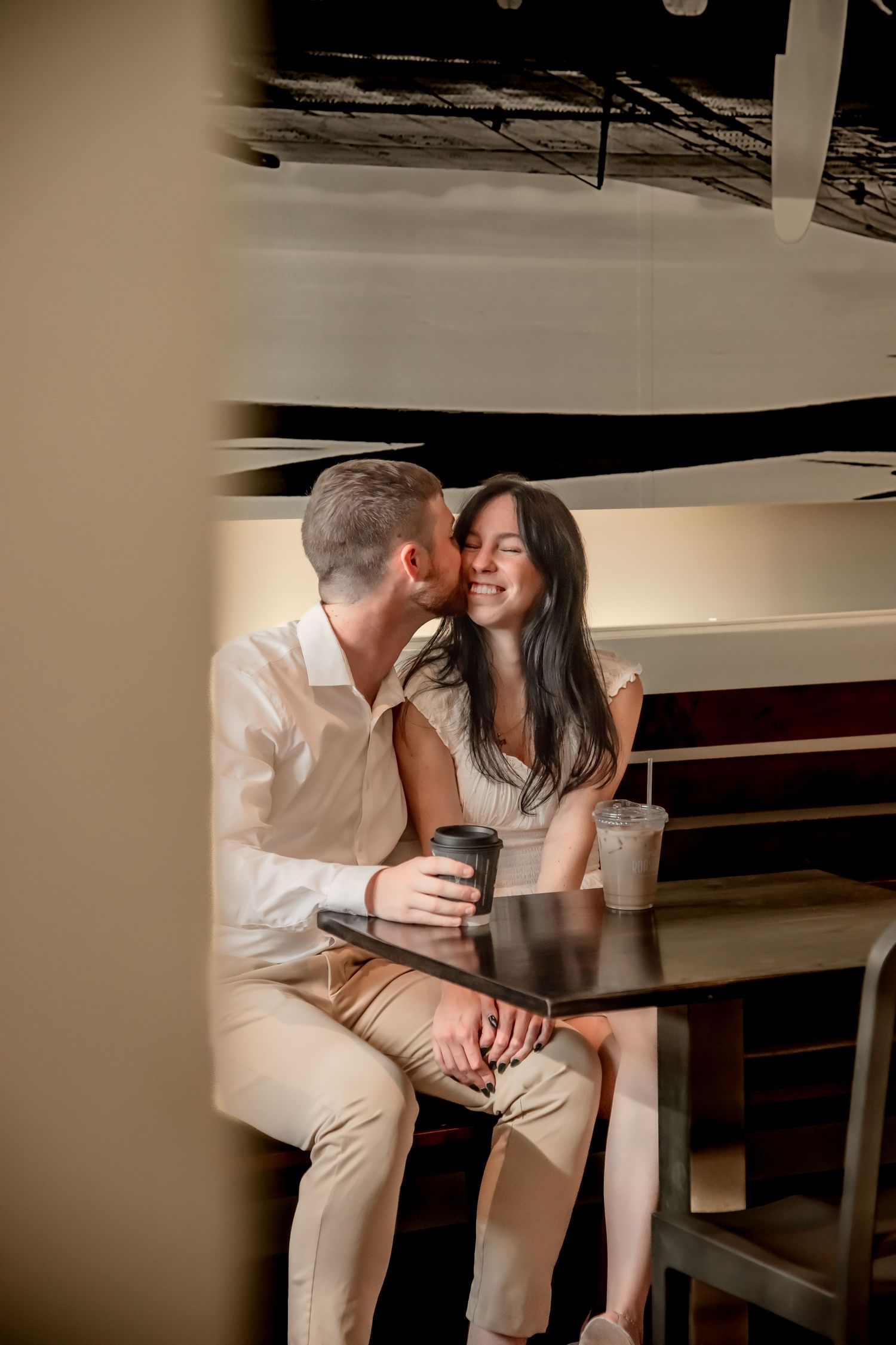A romantic couple shares an intimate moment on a wooden bench in a dimly lit setting.