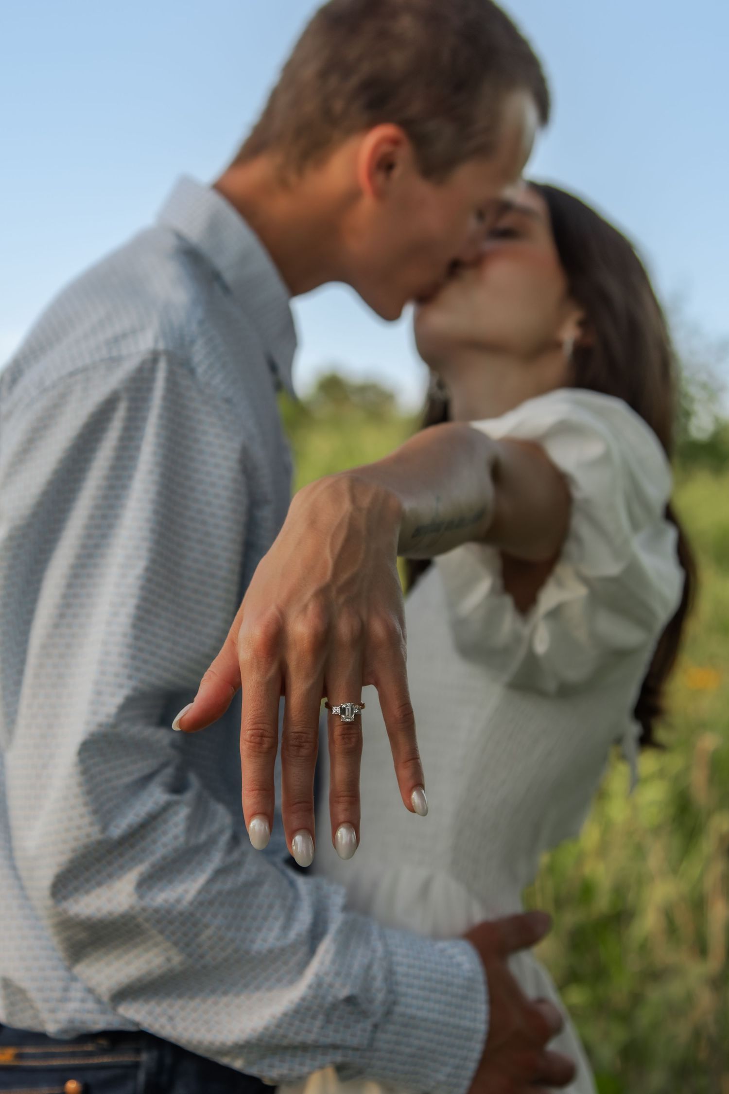 Close-up of engagement ring as couple shares intimate moment outdoors.