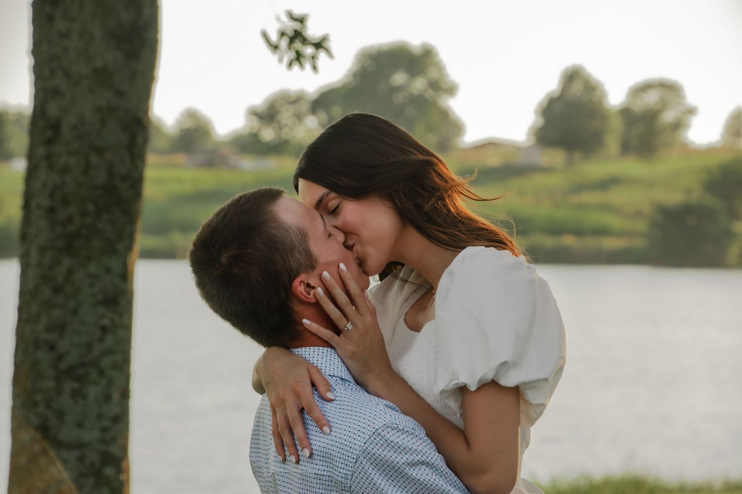 A romantic couple shares sweet kisses by a serene lake as the sun sets.