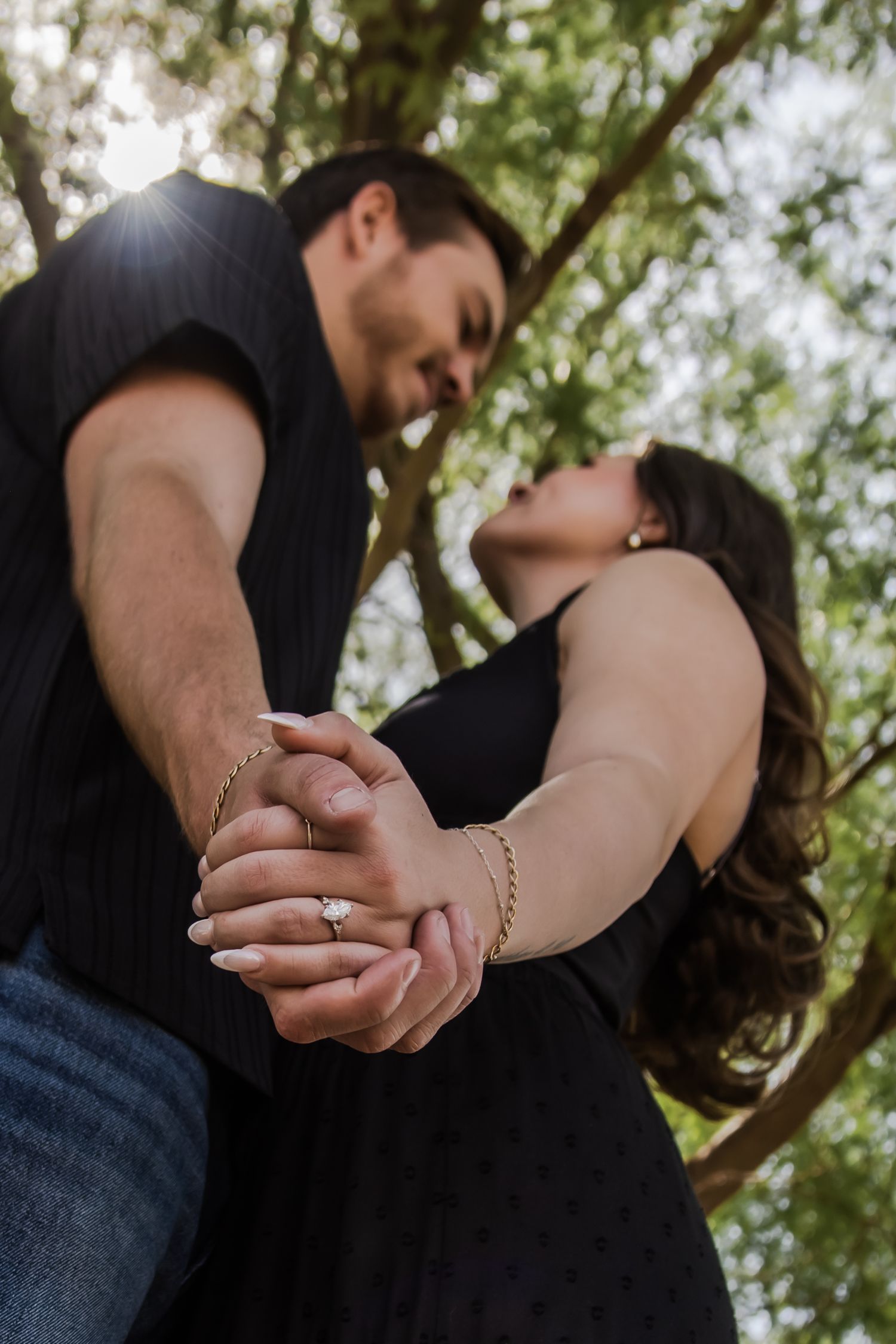 Close-up shots of a couple holding hands outdoors with natural lighting filtering through trees.