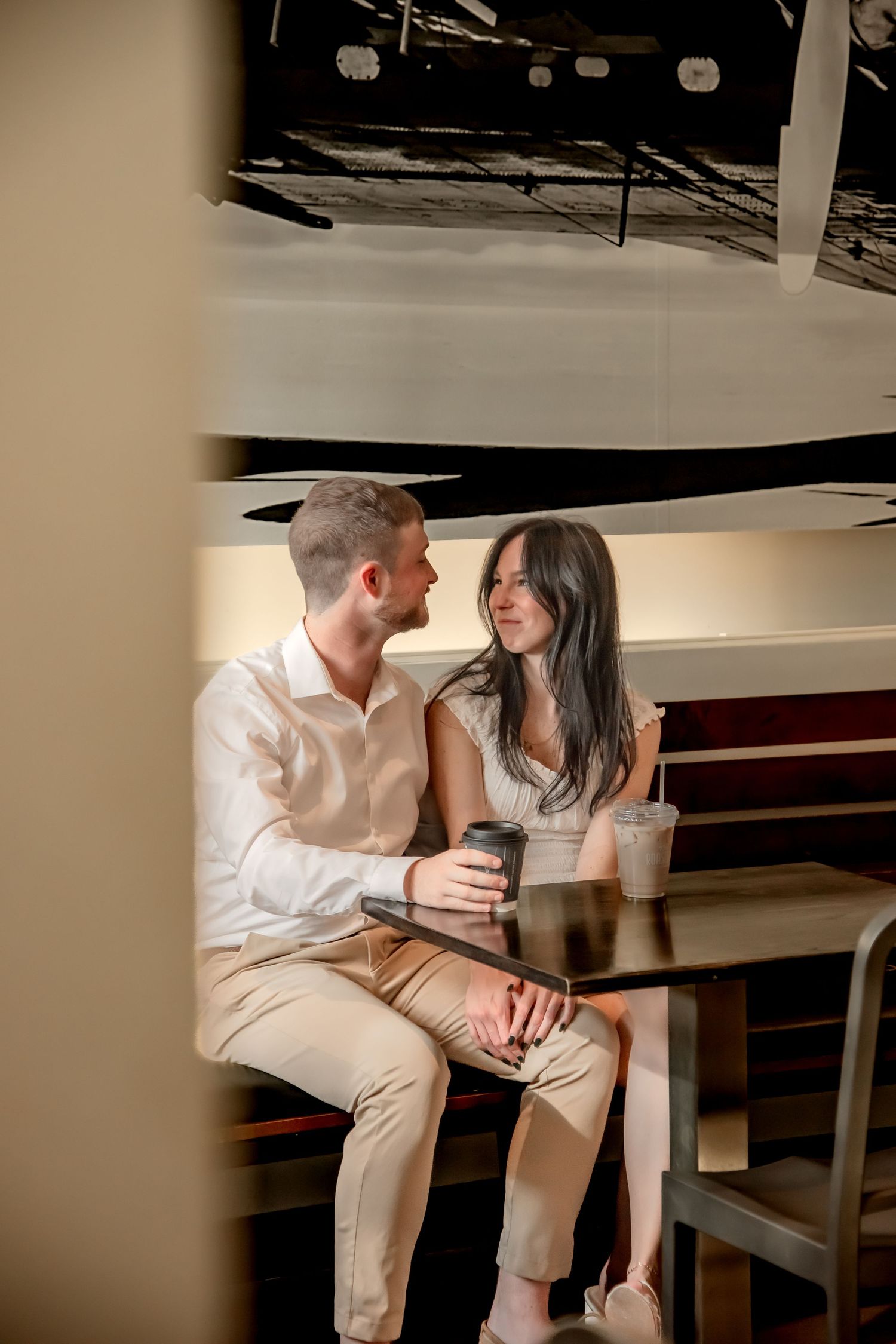A couple sits close together sharing intimate moments in a dimly lit indoor setting.