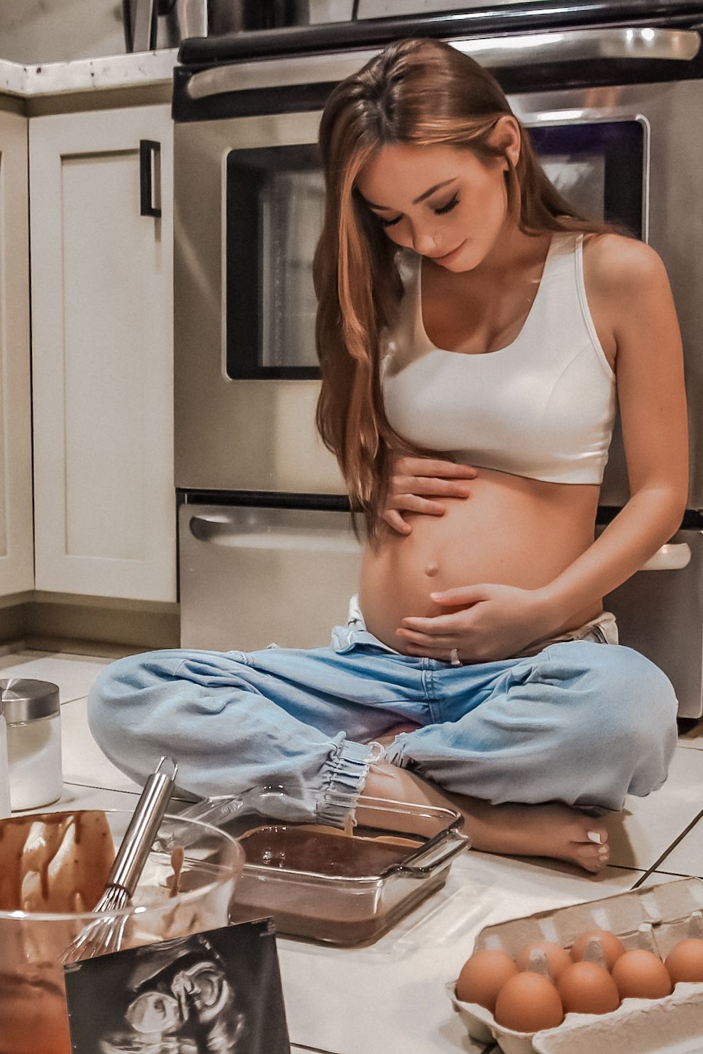Person in white top setting up ingredients and kitchen utensils for baking or cooking on a counter.