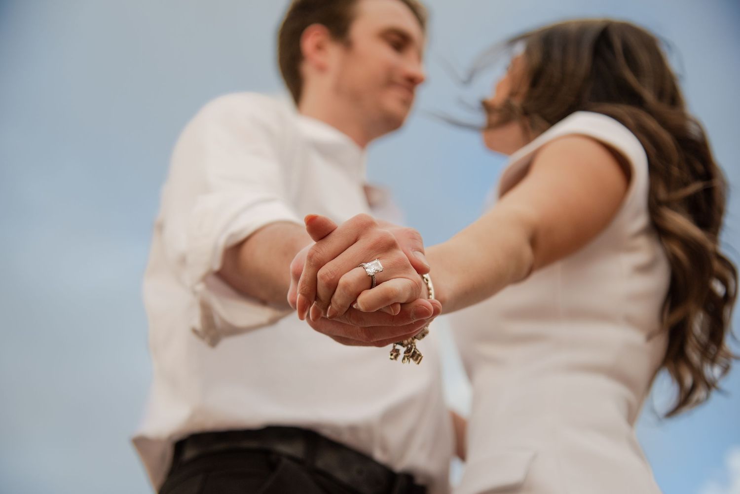 Romantic couple dancing together in elegant white outfits.