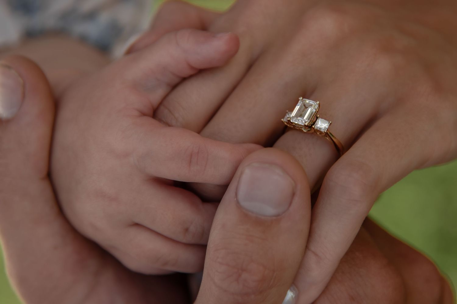 Close-up of hands holding a sparkling diamond engagement ring with a white gold band.