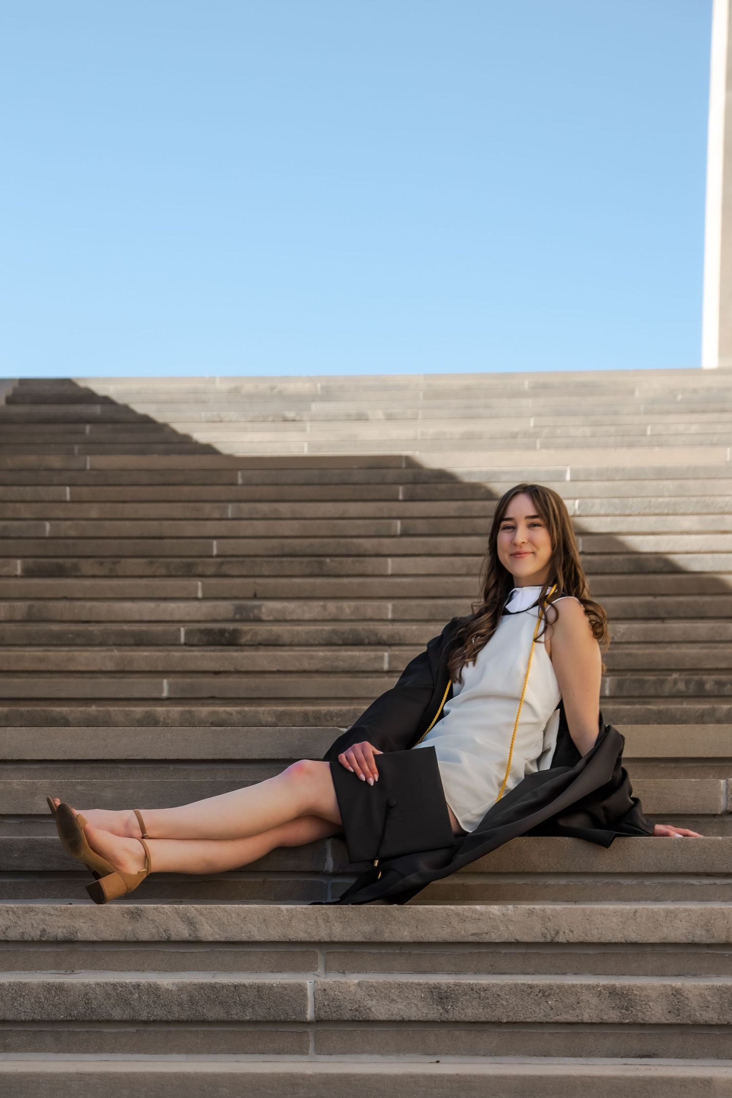 A person in business attire lounges on wide stone steps with a modern architectural backdrop.