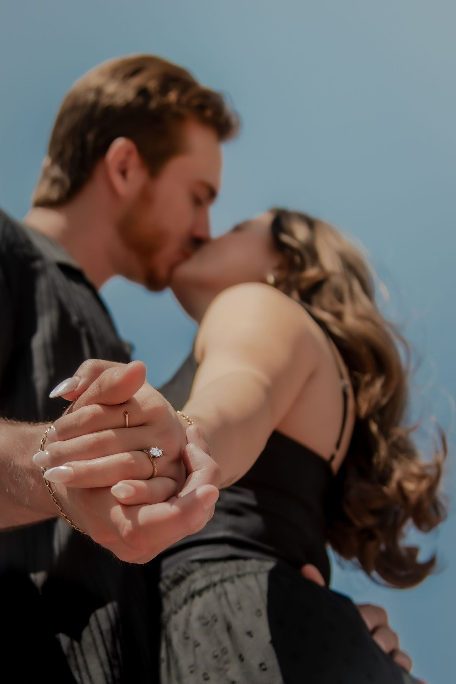 Close-up engagement photo showing ring exchange during romantic moment.