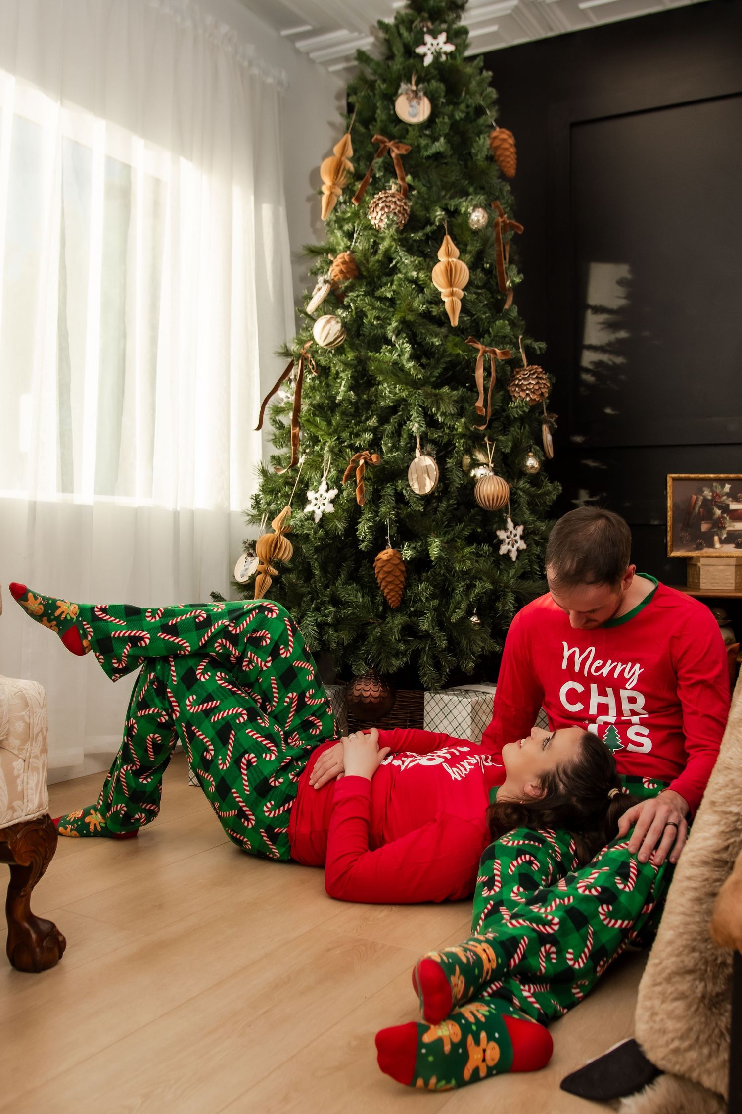 A festive Christmas scene with matching pajamas and a decorated tree in a cozy living room setting.