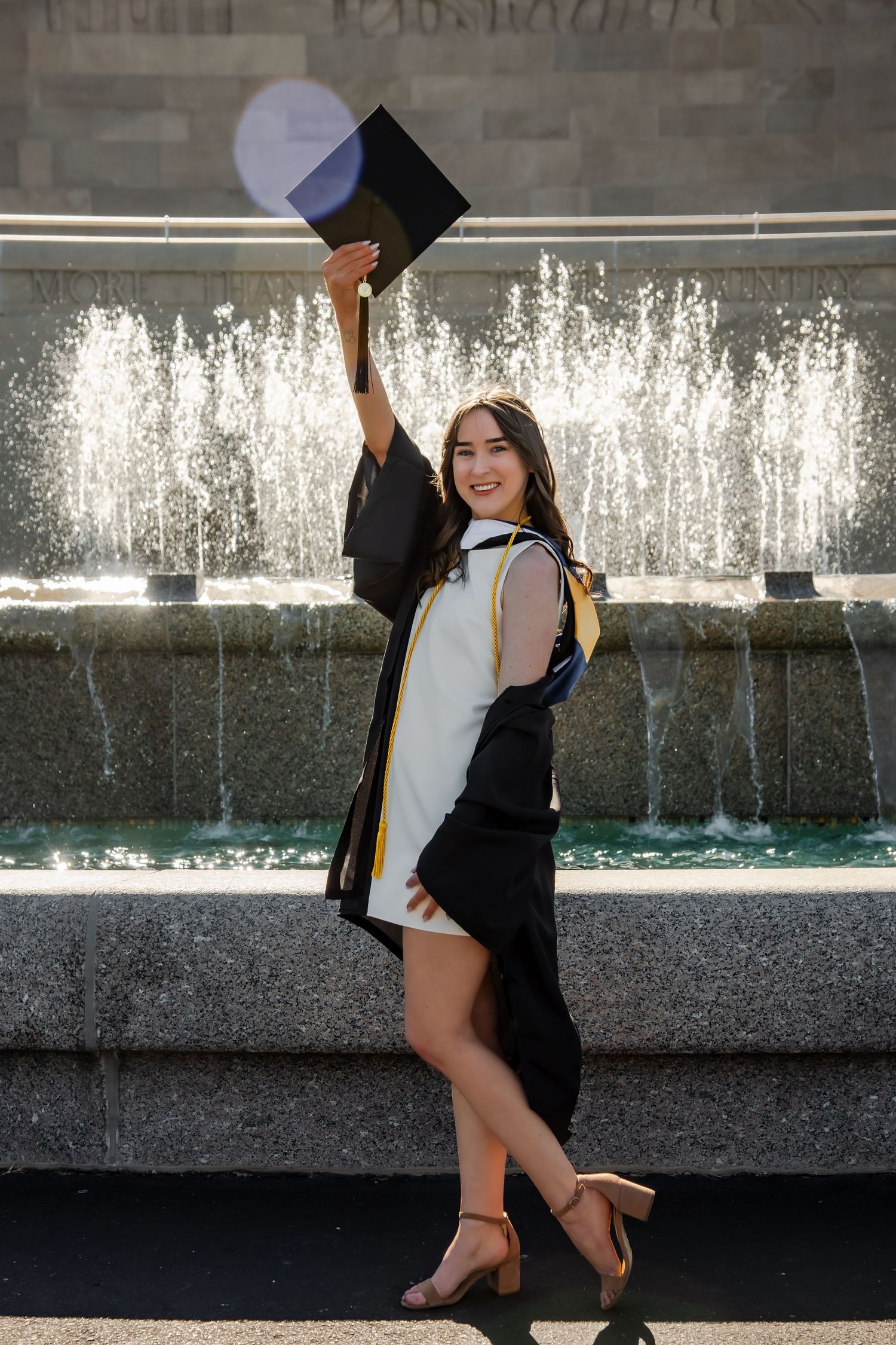 Graduation photoshoot featuring celebratory poses by a water fountain.