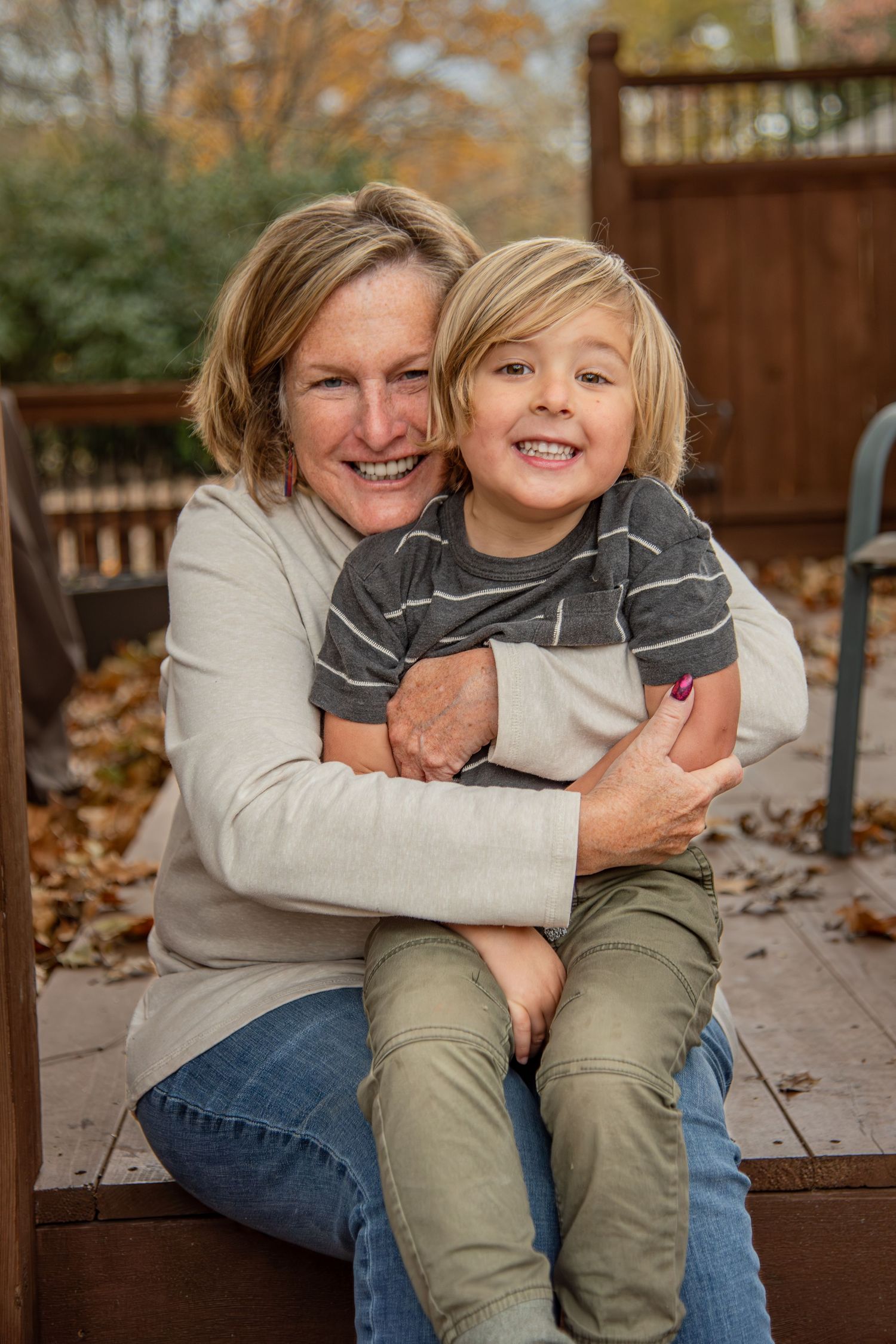 A heartwarming embrace shared on a wooden deck surrounded by fallen autumn leaves.