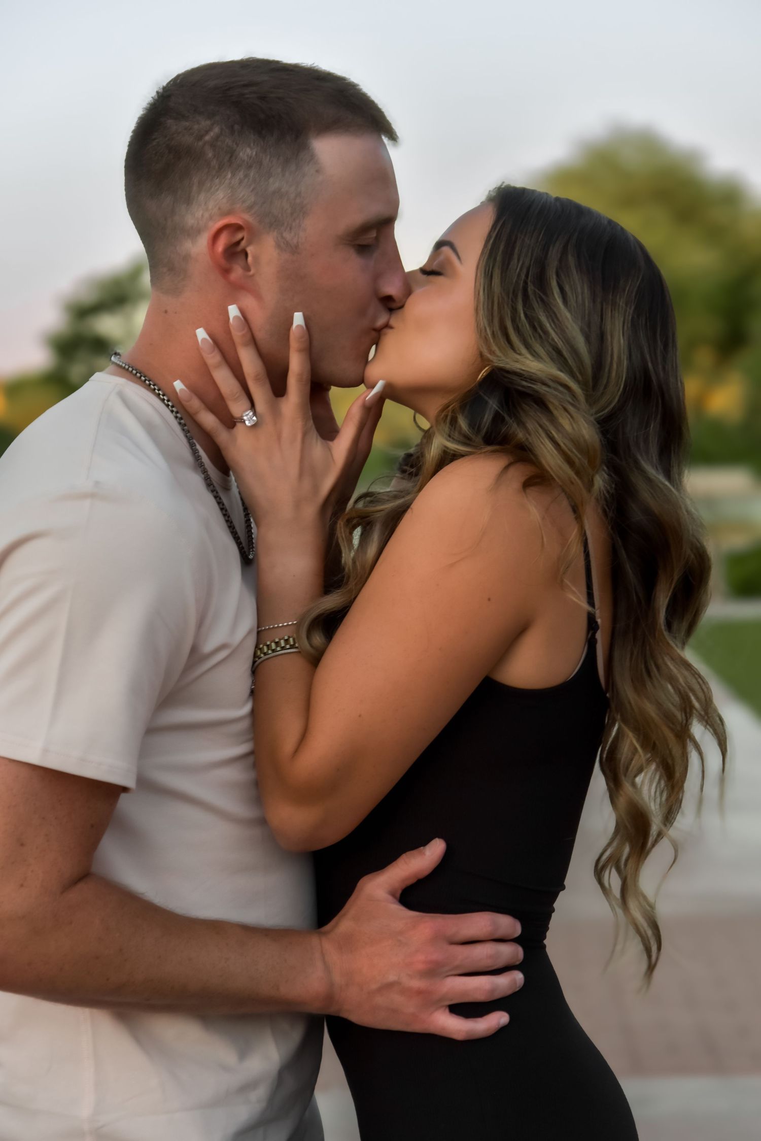 A romantic couple shares a series of intimate kisses in an outdoor setting during what appears to be a photo session.