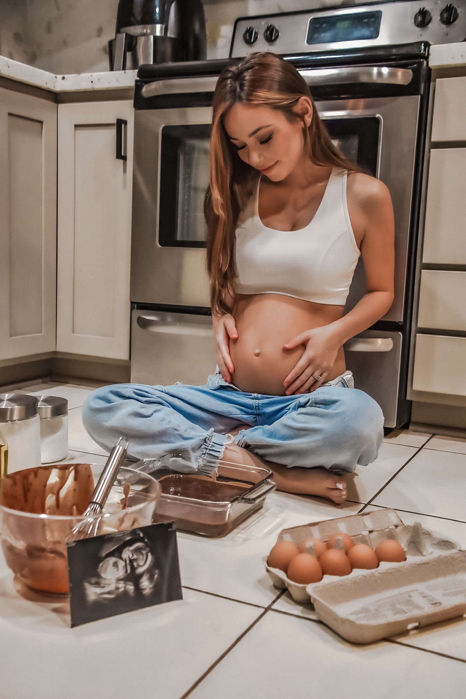 Person baking in kitchen with eggs and baking supplies on counter.