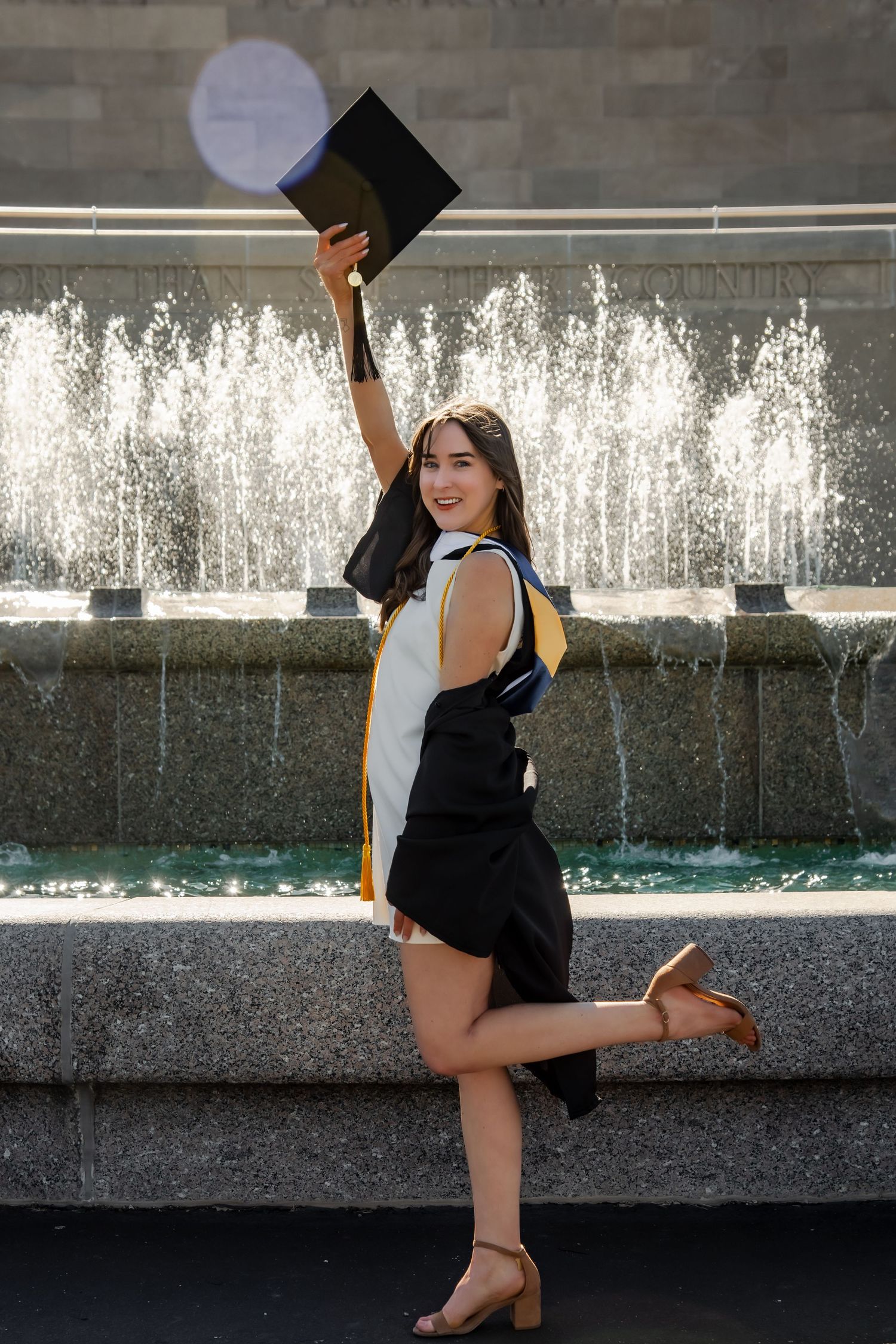 Playful graduation portrait session with water fountain backdrop.