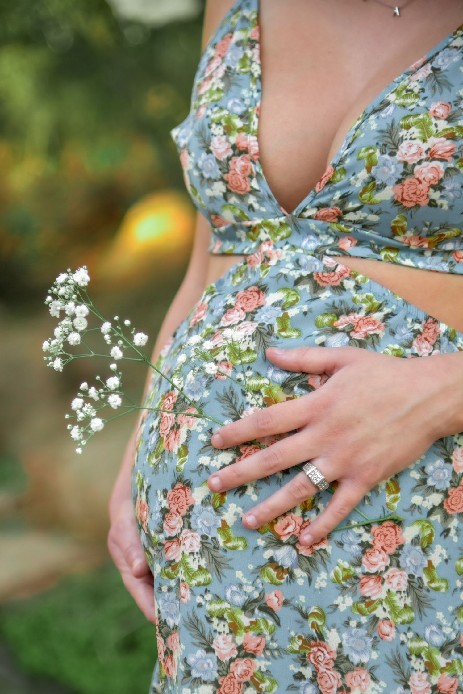 Close-up sequence of a floral maternity dress with hands cradling a baby bump.