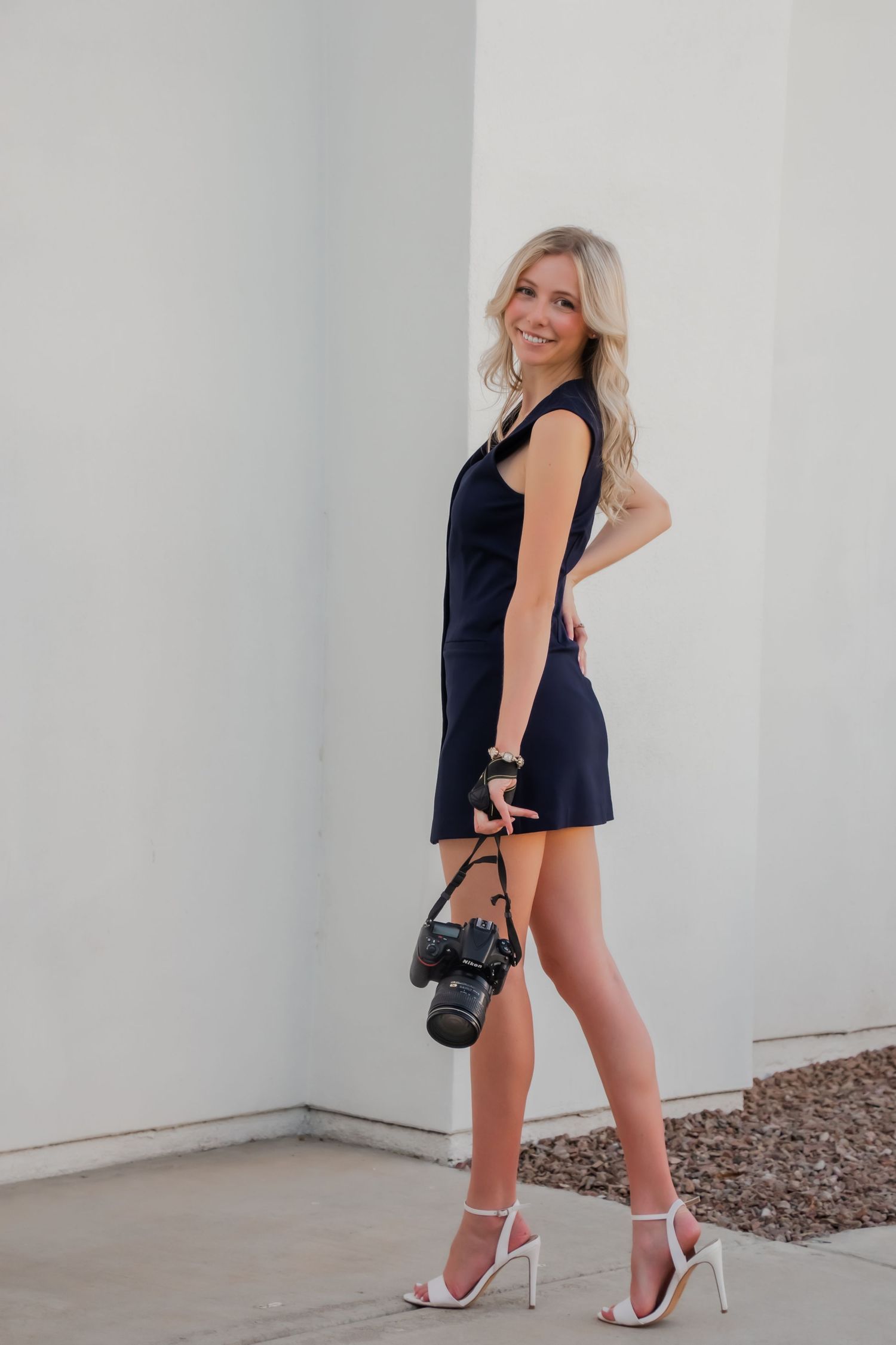 Fashion photographer in navy dress poses with professional camera equipment.