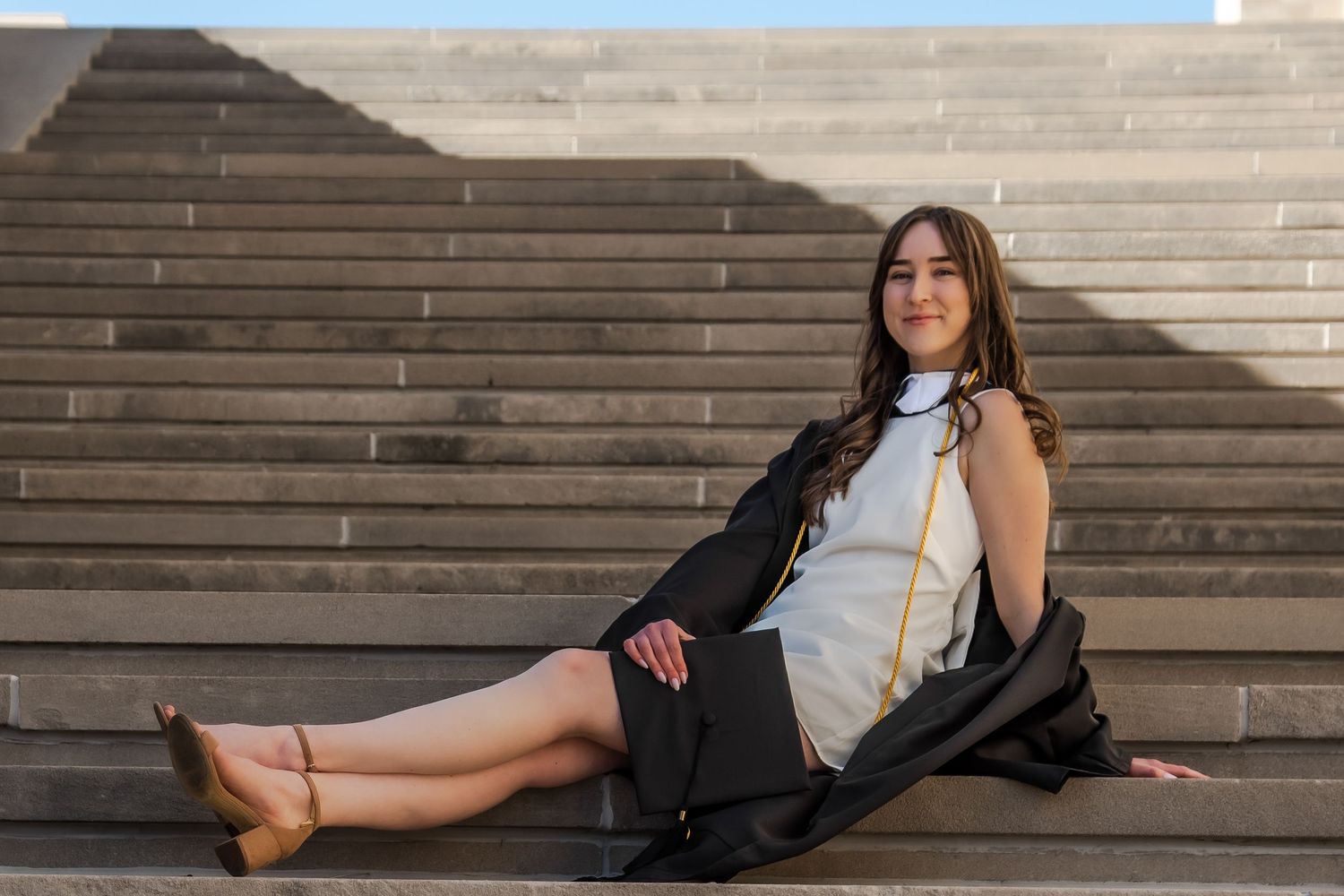 A person in a black blazer poses on concrete steps in multiple artistic poses for a fashion photoshoot.