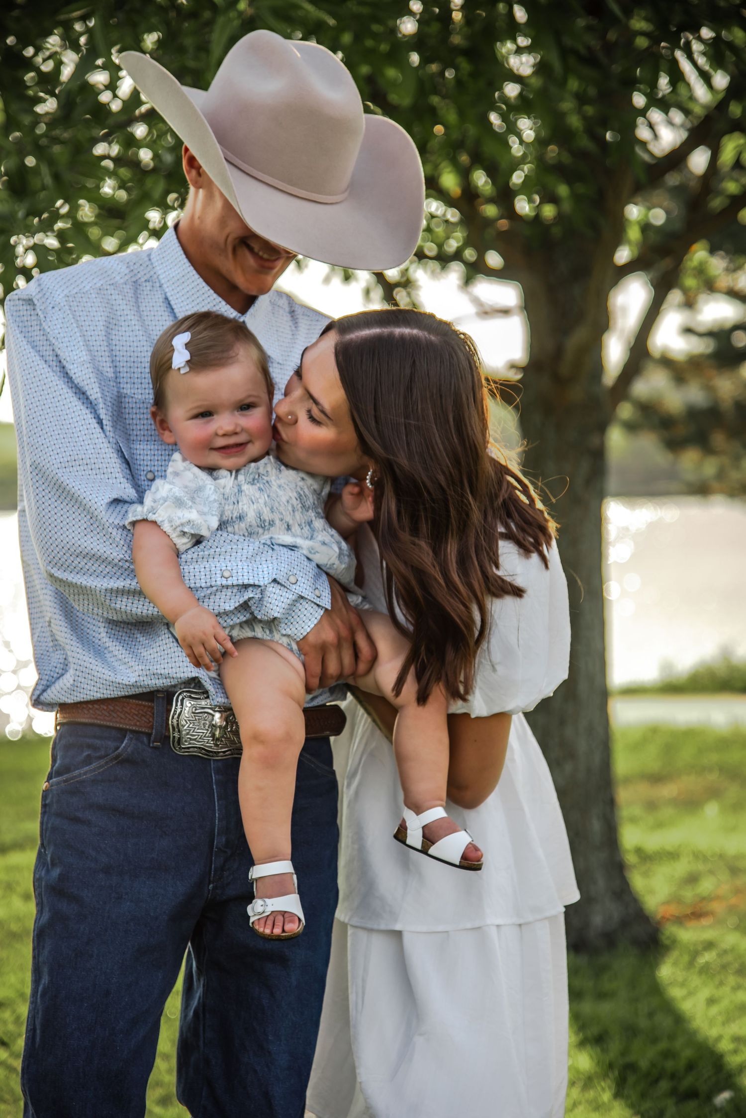 A couple in western attire shares tender moments with their baby outdoors in a series of connected photos.